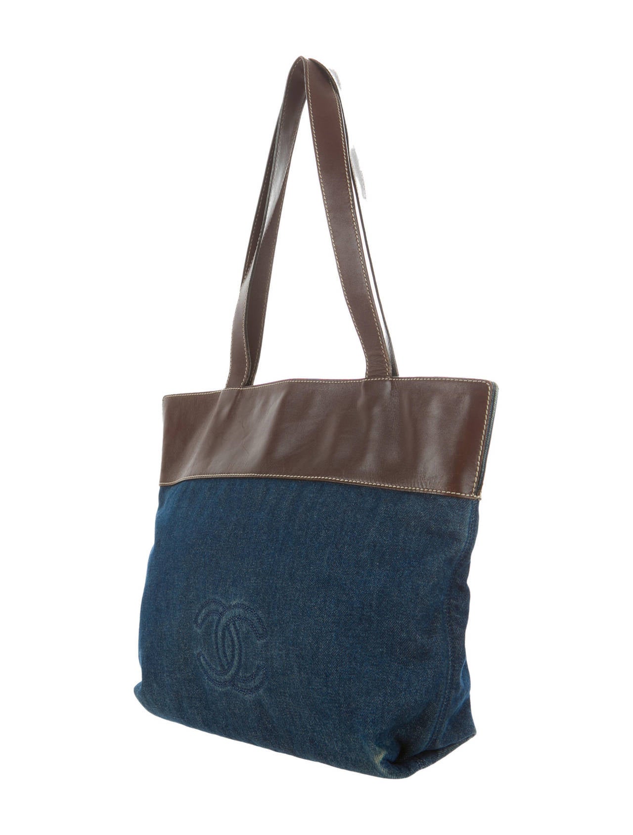 Chanel blue denim tote with stitched logo at front face, white contrast stitching throughout, brown leather top with dual leather handles, two interior zip pockets and top magnetic snap closure. Serial number reads 611505. 

Shoulder strap drop
