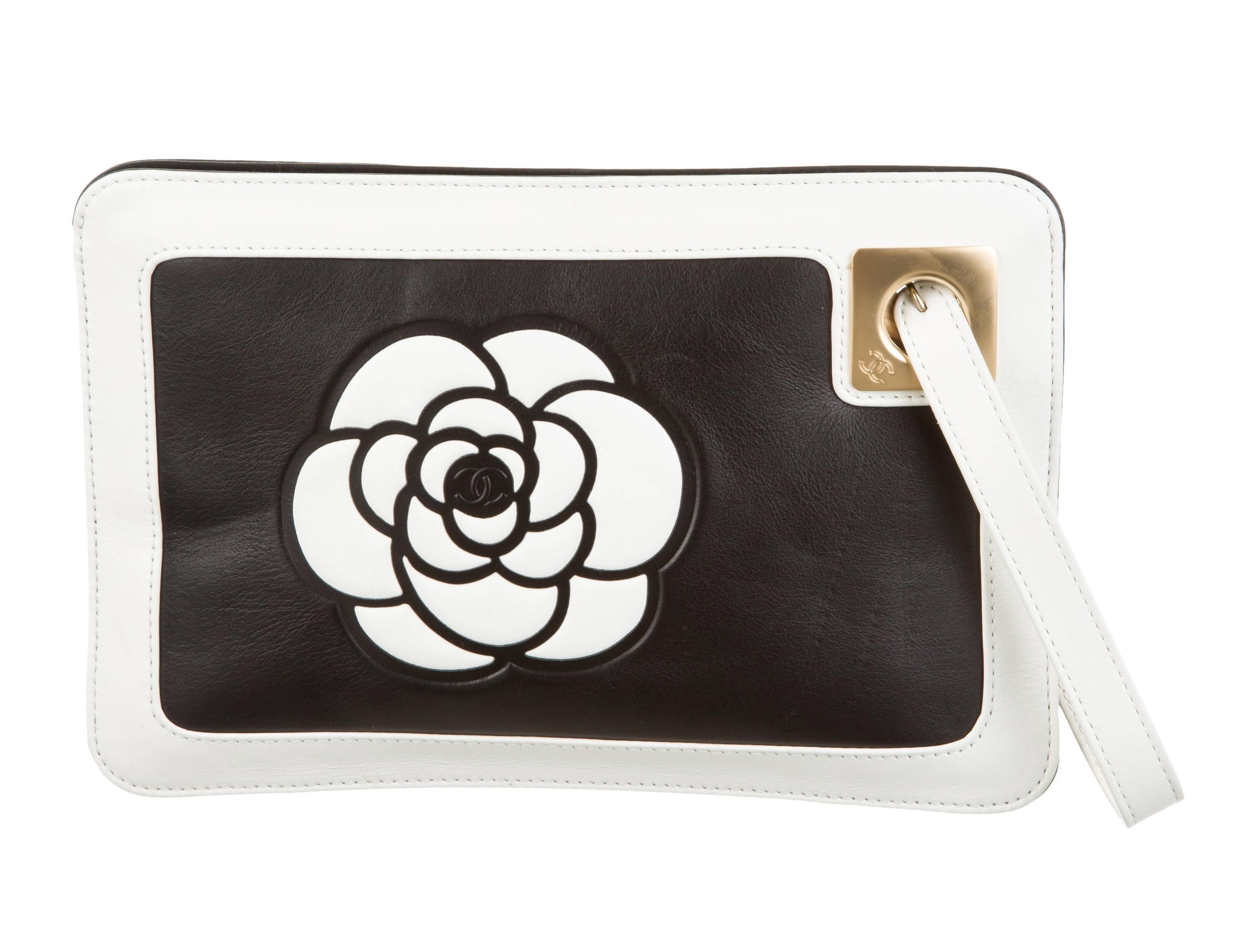 Black leather Chanel Camellia Wristlet clutch with gold-tone hardware, white leather trim, flat wrist strap, Camellia accent at front, logo at back, beige canvas lining, single pocket at interior wall and zip closure at top. Serial number reads