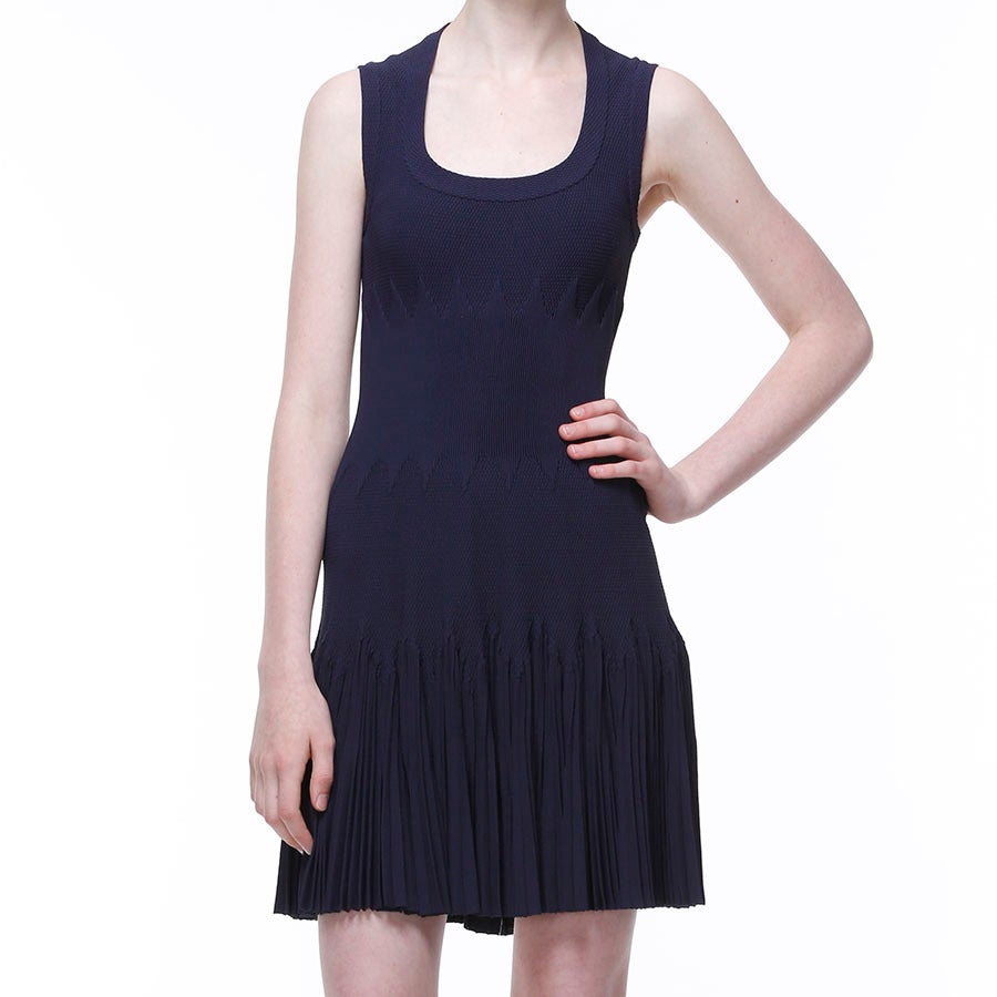This navy blue honeycomb knit dress is sleeveless, has a scoop-neck and a zigzag ribbed waistband with a pleated frill hem. This dress is fitted to the hip, has a loose fitting pleat skirt and a hidden zip centre-back fastening. 80% viscose, 10%