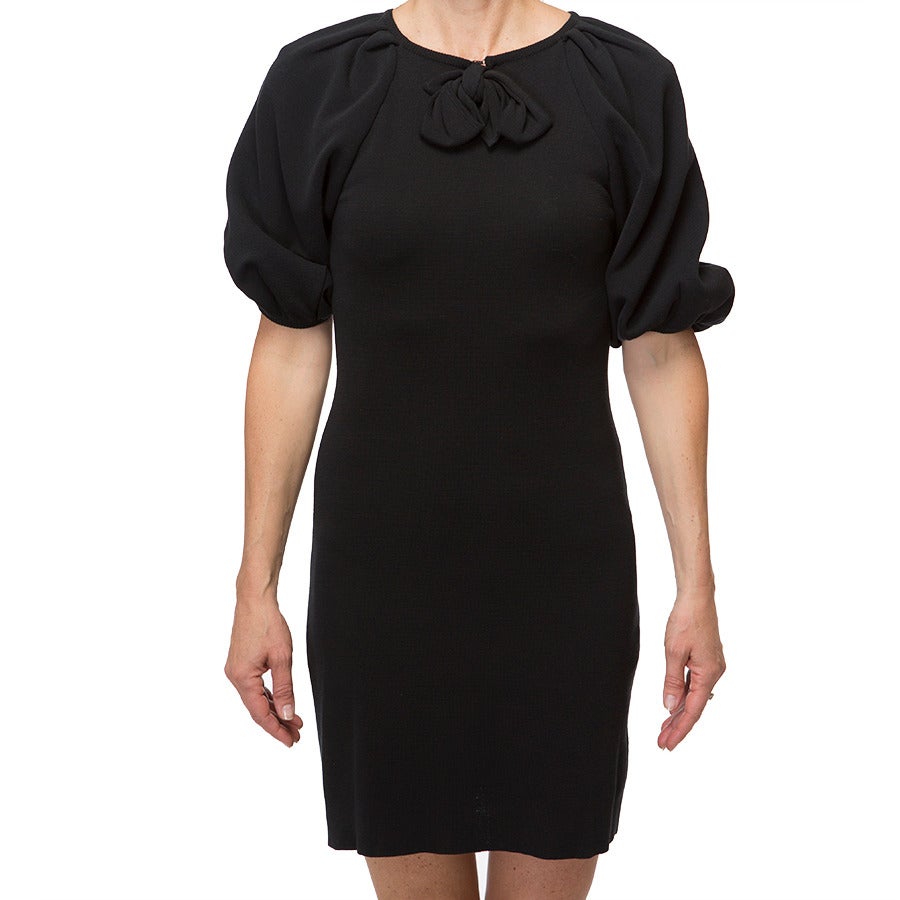Giambattista Valli black fitted dress with puffed sleeves gives a beautiful and flattering silhouette. The neckline features a small keyhole with hook and eye closure and a small bow. Slight stretch to fabric.
- Size: Italian 38
- 3/4