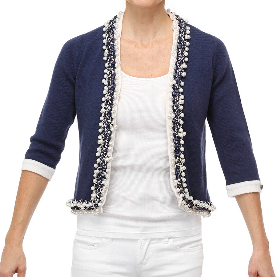 This Chanel bicolor cardigan is exquisitely hand-embroidered by Lesage along neck, front and hem. Approx. 300 white resin pearls are attached with miniscule metal rings to a hand-braided trim in navy/blue/ivory/white.  A small grey metal oval with