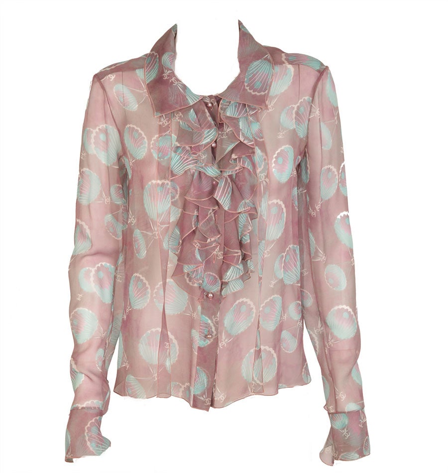 Perfect for summer or resort, this 2 piece CHANEL blouse in aqua & lilac print with seashells and CC logos,  is ultra feminine with ruffles galore on collar, cuff and front of blouse as well as armholes of the vest.  The blouse and vest may be worn