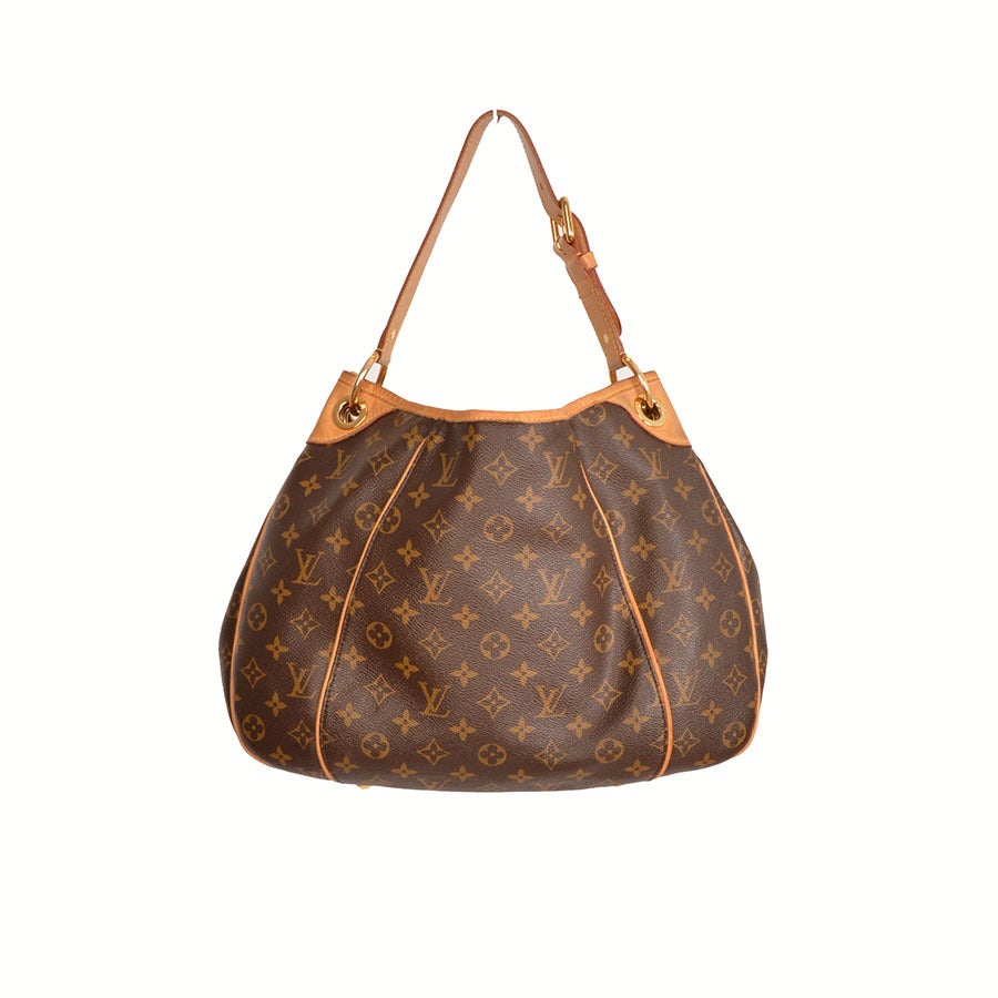 Louis Vuitton brown and tan monogram coated canvas shoulder bag with vachetta leather trim, brass hardware a, beige alcantara suede lining and concealed top snap closure. Includes original dust bag. Date code reads MI2008
- Louis Vuitton brown and