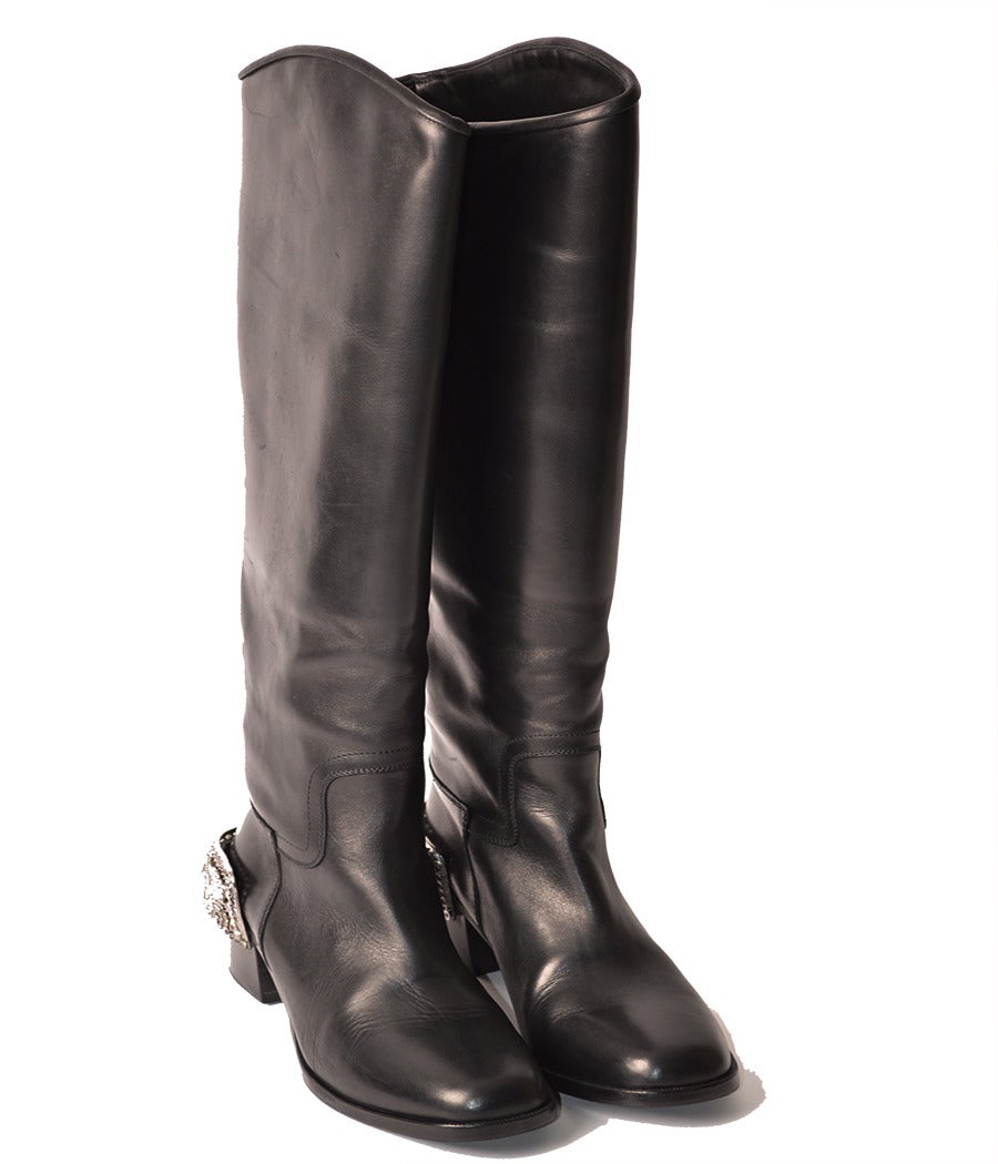 Classic black leather riding boots in sturdy black calf features exquisite 1.6” high rectangle shaped spurs in silver metal with various Chanel  codes: lion heads, stars ,flowers. The knee high boot silhouette has a comfortable slight rounded toe