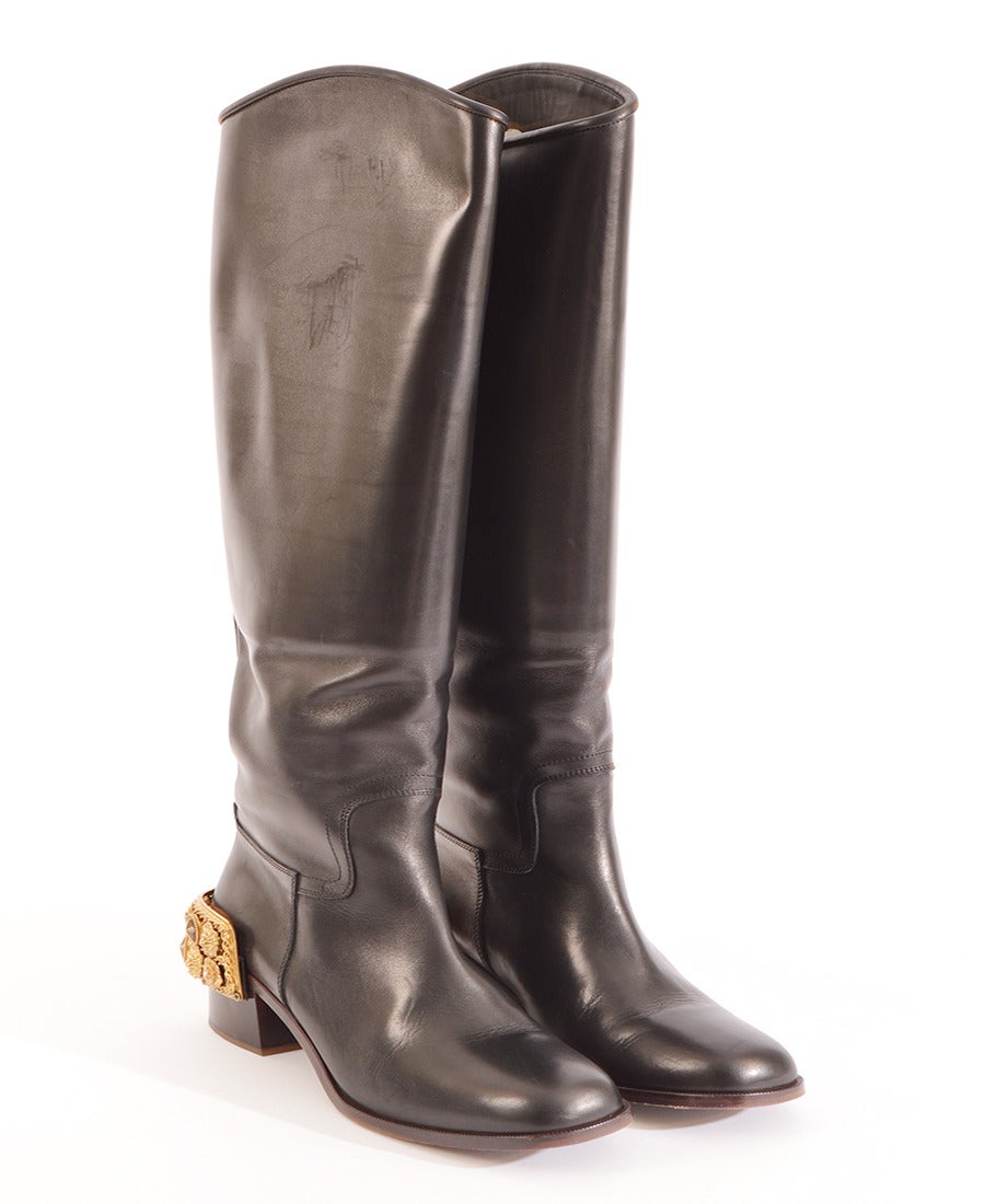 Classic black leather riding boots in sturdy black calf features exquisite 1.6” high rectangle shaped spurs in gold metal with various Chanel codes: lion heads, stars ,flowers. The knee high boot silhouette has a comfortable slight rounded toe with
