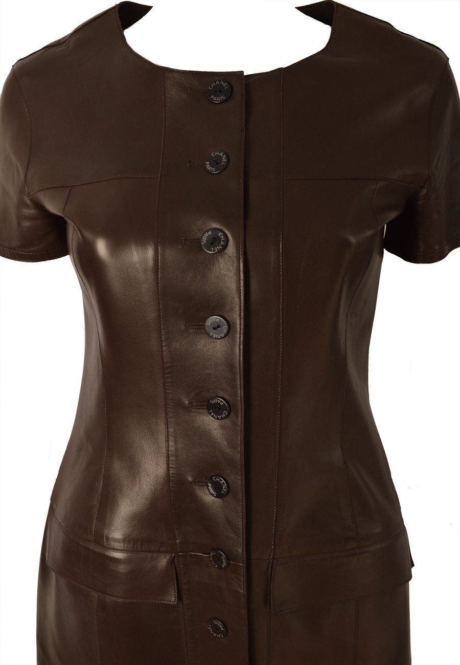 Chanel dark brown short sleeve leather dress/coat. This unlined body hugging leather dress with button front and two flap breast pockets, combines Chanel’s signature butter soft lambskin with artisanal workmanship:  four front panels and twelve back