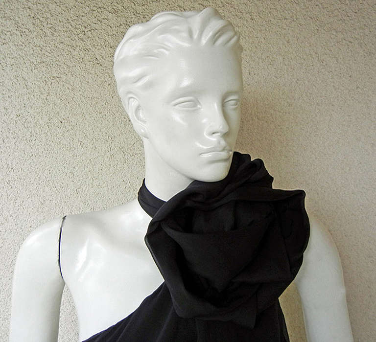 Emanuel Ungaro 1930's inspired black silk chiffon asymmetrically draped gown. Adorned at neckline with an oversized circular flower with button neck closure. Step-in back with side zipper closure and asymmetrical cross strap. Blouson bodice; hand