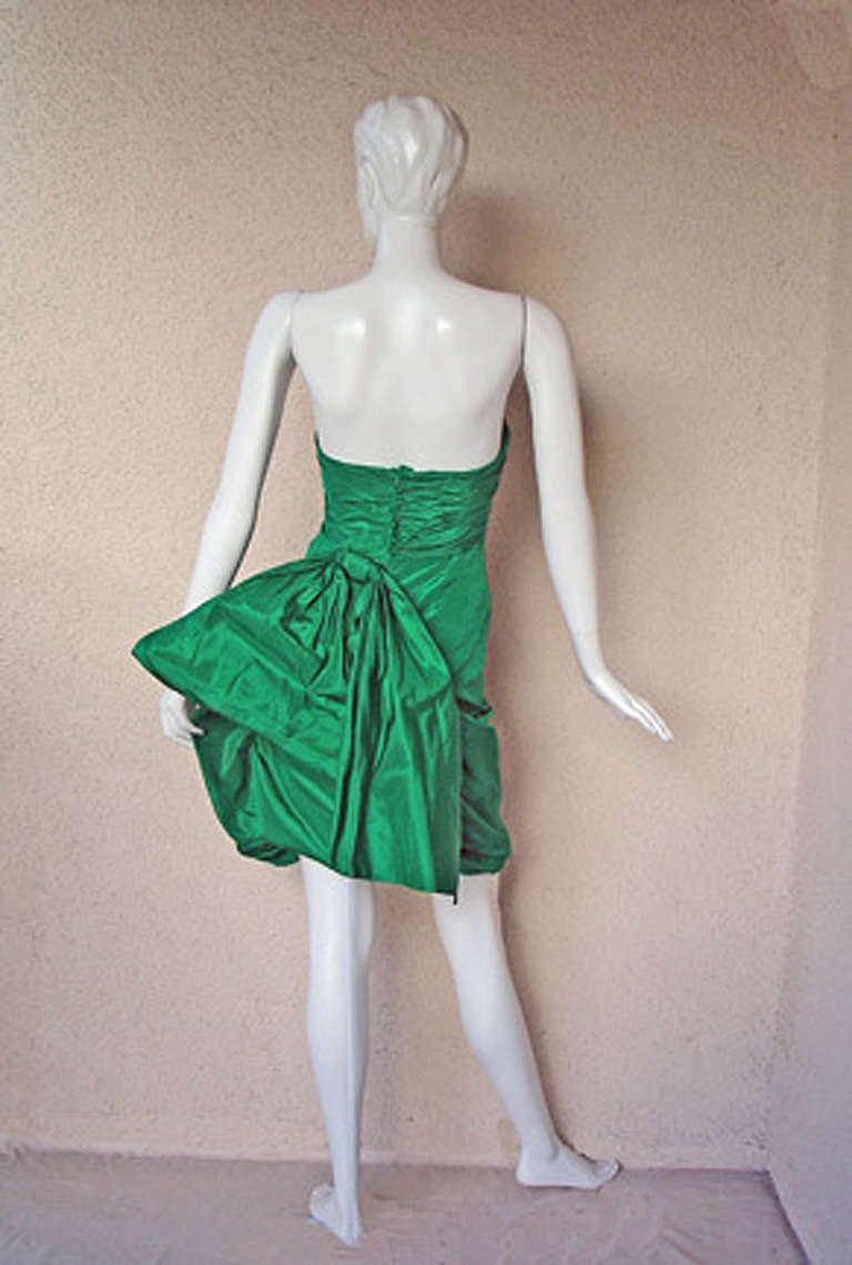 A sculptured silk taffeta creation by Emanuel Ungaro.  The silhouette is inspired by many of the creations of noted haute couture designers of the 40's and 50's. 
Fashioned of a deep rich emerald green silk taffeta with strapless ruched inner
