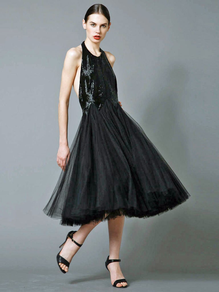 Alexander McQueen seductive backless halter dress with bodice of hand sewn bugle beads complimented by full pleated layered tulle net skirt. Beaded bodice boasts inverted triangular pattern at waistline. Evening dress fashioned of black silk net and