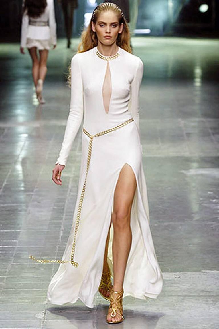 Alexander McQueen 2006 Winter white silk crepe gown with plunging net neckline.  Gold chain enhancements with sexy thigh high slit. Long slender sleeves with wrist zippers.   Fully lined. Back zipper closure.

Size: IT40; bust-33