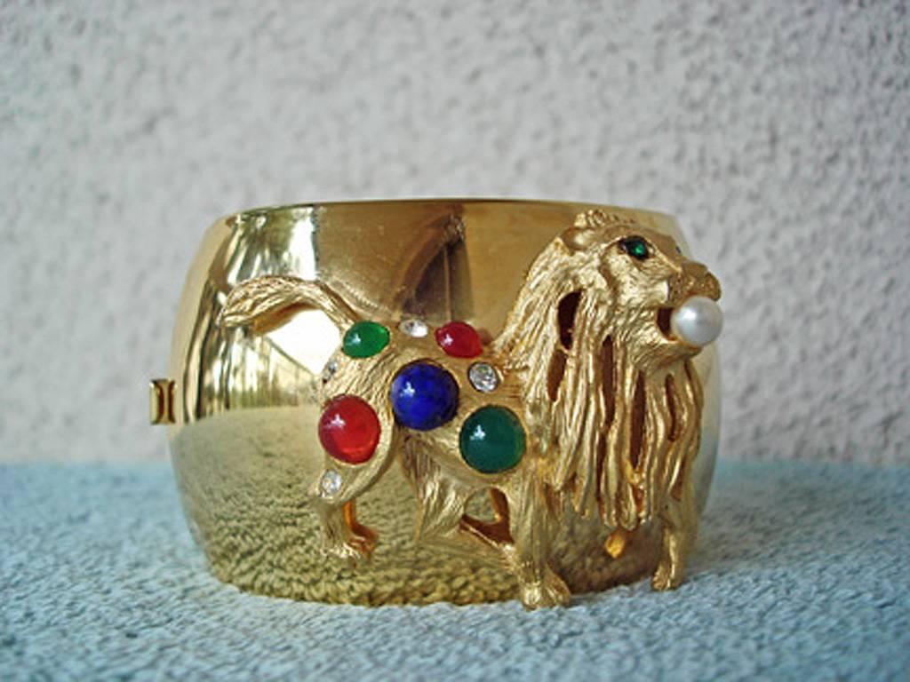 Circa 1980's large gold metal cuff bracelet by Pierre Balmain Paris. Oval shape wide cuff with insert lock closure. Adorned with large dimensional lion enhanced with faux emerald, carnelian, lapis stones. Single pearl and tiny clear crystals. Signed