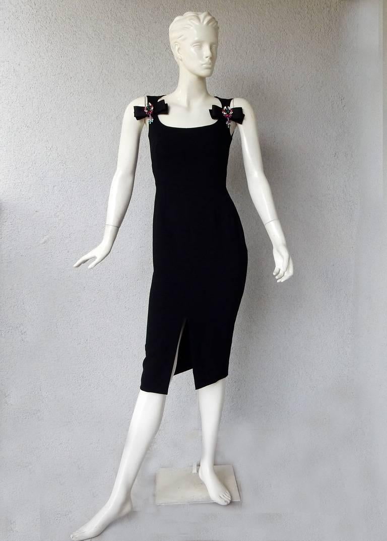 New with tags Dolce & Gabbana 'lil black dress' fashioned of black crepe wool and silk.  Bows with multi jewel adornments at bodice.  Fully lined.  Slit front.  Back zipper closure.  Designed to give the wearer a very flattering fit as all Dolce &