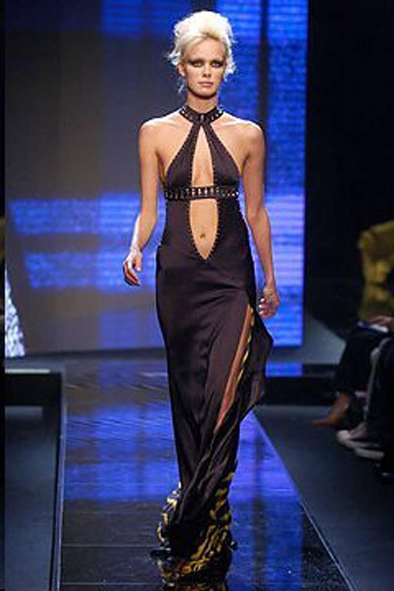Early 2000 Versace cut-out halter gown with thigh high slit and plunging neckline.  Trimmed with square faceted silvertone grommets.  Bias cut with asymmetric open back with long full tiger print panel.  Zipper closure.  Uniquely designed and