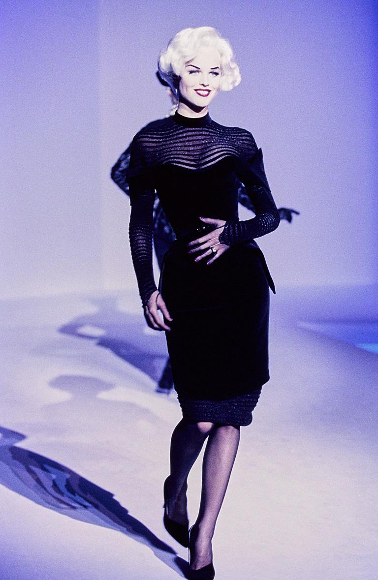 Autumn-Winter 1995-96 Thierry Mugler black velvet dress with transparent knit. Form fitting bodice cinched waist with matching black velvet belt. Dress is identical to that in the photo of the book 