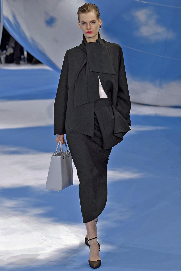 Christian Dior 1950's inspired demi couture highly stylish suit by Raf Simmons for the Fall 2013 collection.  Stunning suit opened the runway show as look #1.

Fashioned of fine black wool constructed with a tie neckline; swing jacket with bell