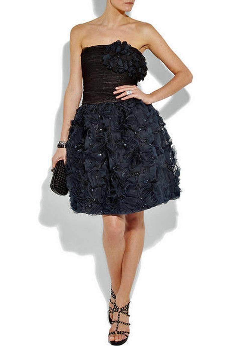Oscar de la Renta strapless lace and silk corsage cocktail dress offered in brand new condition.  Hand ruched black lace bodice with large attached rosette corsage.   Bodice extends into navy blue tulip skirt adorned with rosettes and twinkling