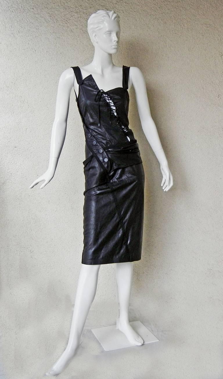 John Galliano's 2000 collection for the House of Dior eighteenth-century inspired asymmetrically cut dress fashioned of black lambskin leather. 

Dress features a gathered pulled up bustle style skirt with lace-up bodice and side rubber button