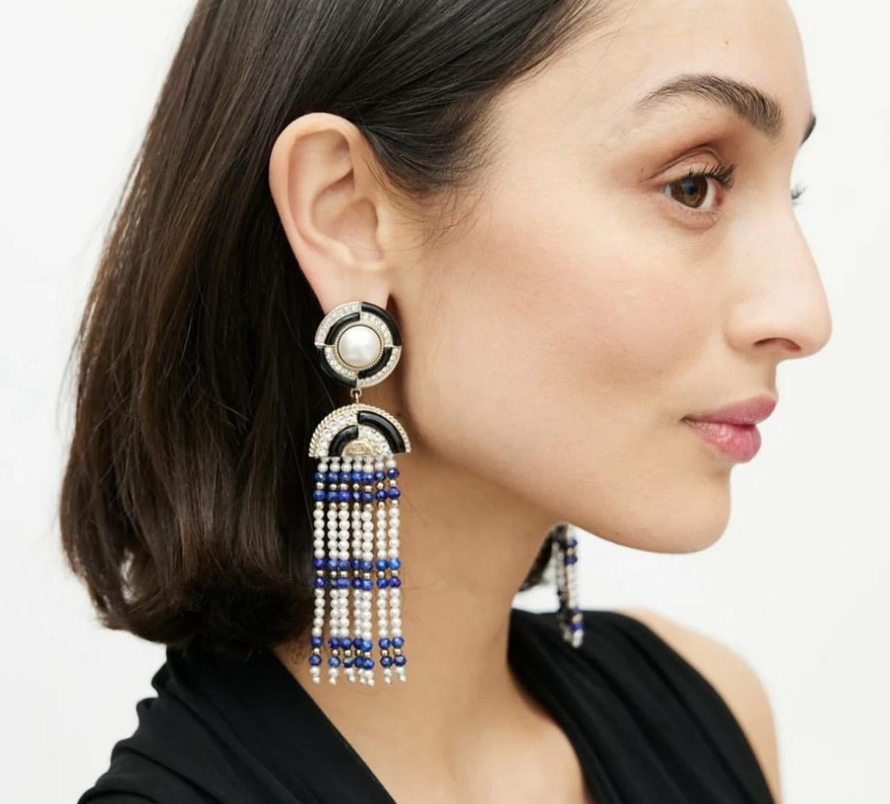 Aggiungi un tocco di eleganza senza tempo alla tua collezione di gioielli con questi splendidi orecchini Chanel a lampadario! Questi orecchini sono della collezione Autunno 2019. 

Sono impreziosite da cristalli con piccole perline bianche e blu che