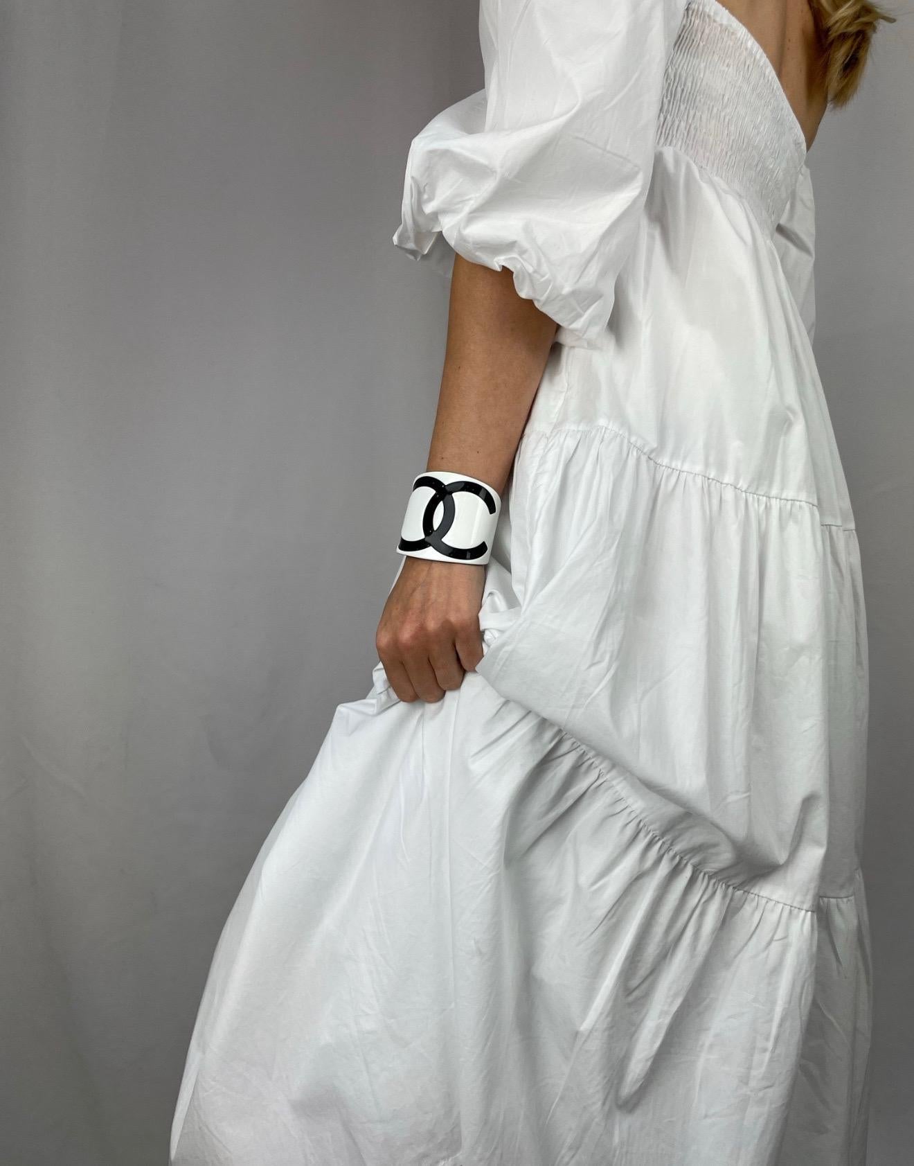 Un impresionante brazalete oversize Chanel Monochrome CC de la década de 2000. Fabricado en resina. Con un gigantesco logotipo CC negro entrelazado sobre fondo blanco para crear un brazalete monocromo realmente icónico. En muy buen estado, firmada,