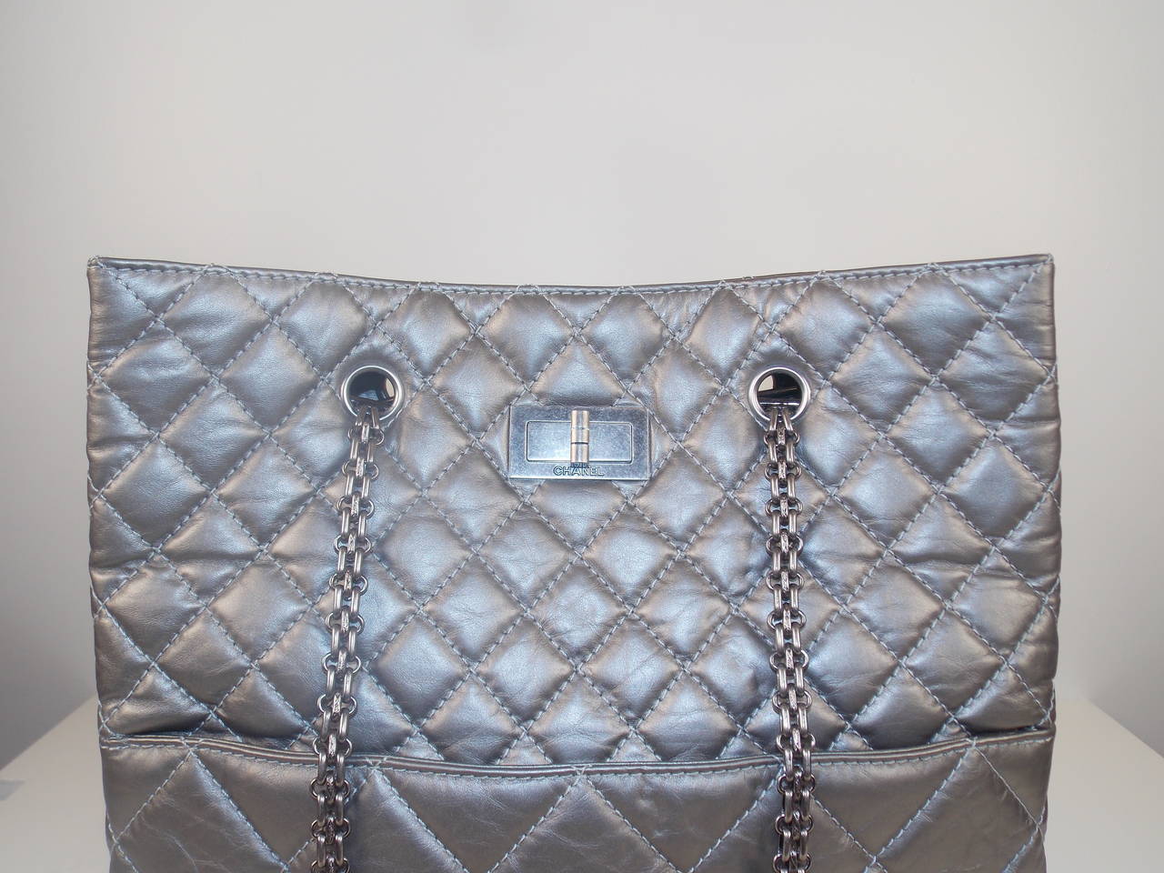 This Chanel Sample Tote is a one-of-kind produced only for the runway.  The tote features diamond quilted matte gray calfskin leather with a chain double shoulder strap, snap closure, an outside front pocket and an inside pocket with zip closure. 