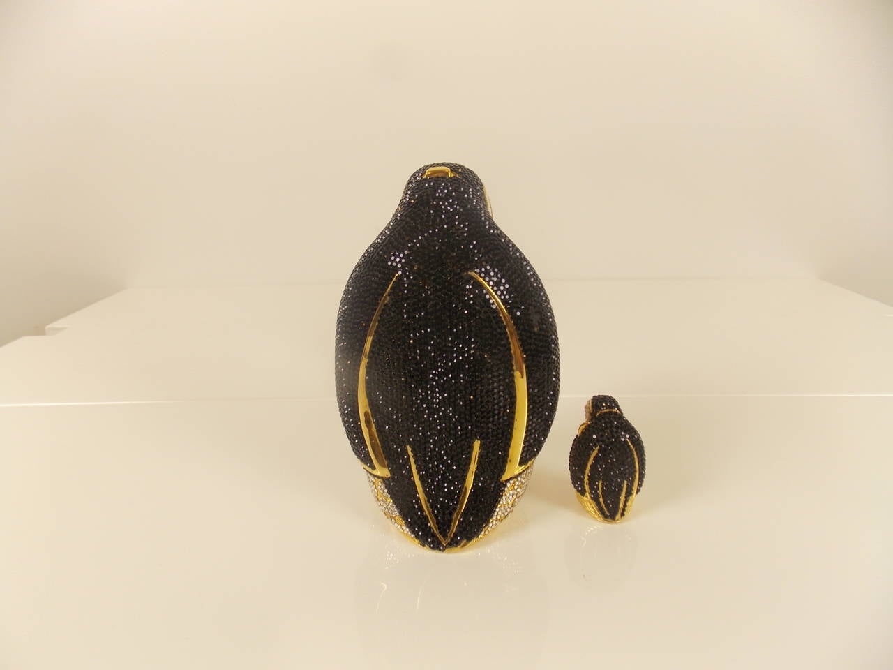 Penguin clutch with gold chain strap, small penguin box inside and comb.

Full bead white, silver, and black crystal penguin with black cabochon eyes, push button opens to gold leather lining, coin purse, mirror and comb. Stamped: Judith Leiber,