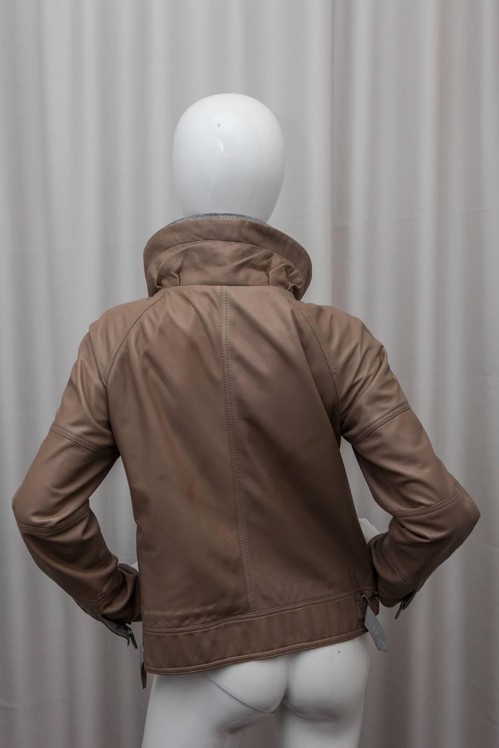 Tan leather jacket with grey lining, snap and zipper closure and front pockets.
