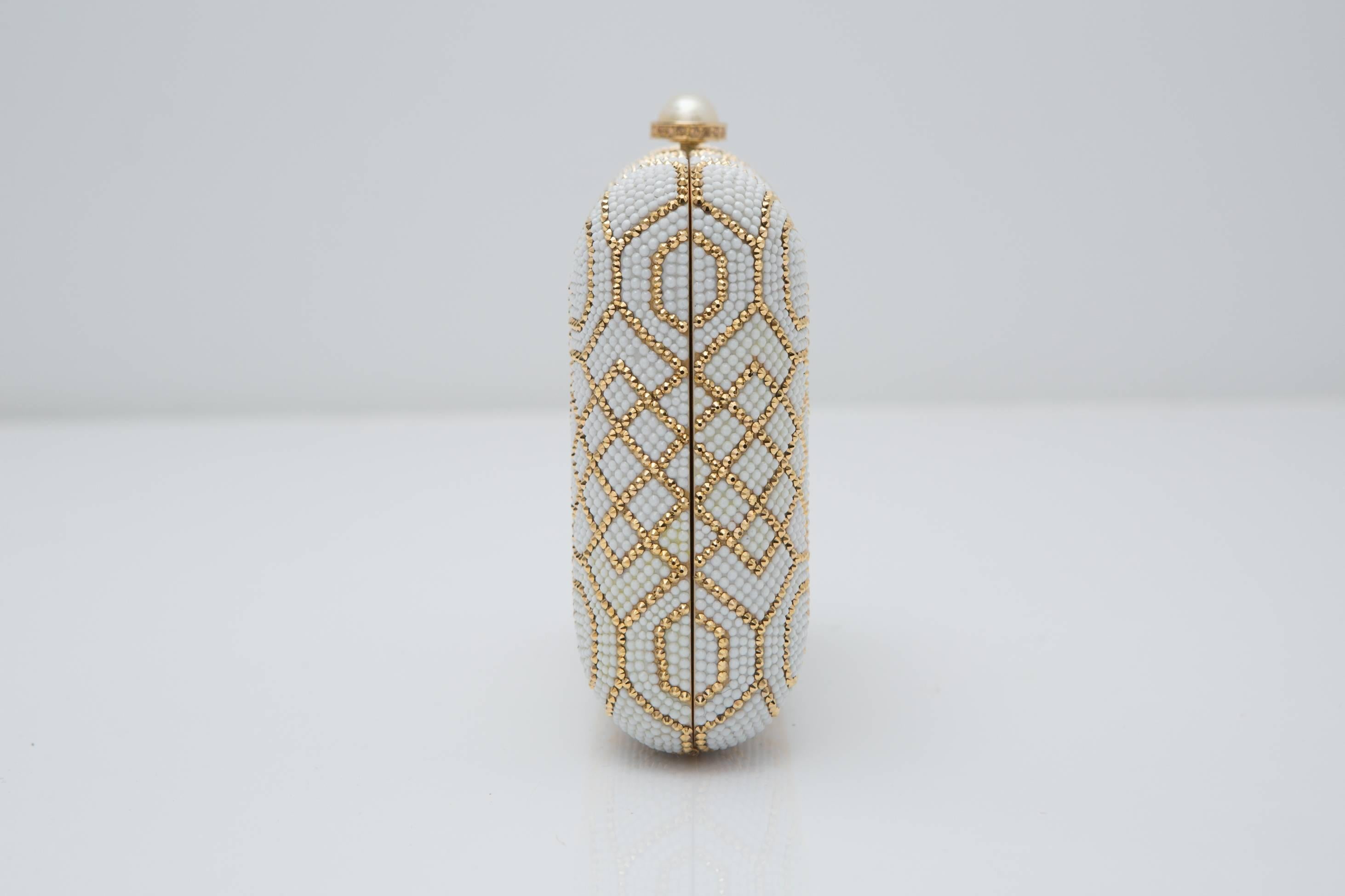 Ivory and gold patterned clutch, with pearl button closure detail.