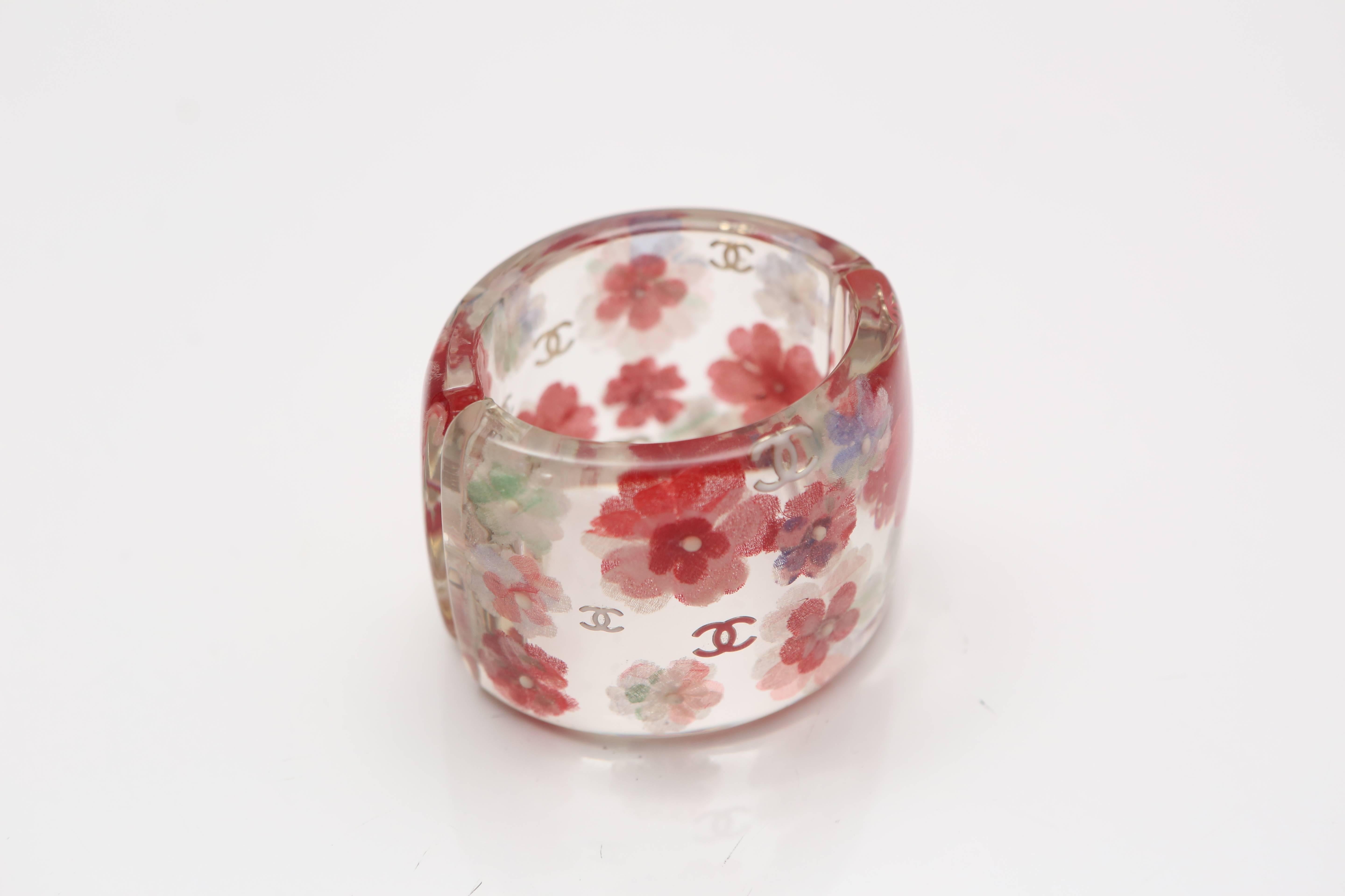 Lucite transparent cuff with red and white cut out flower detail and CC logo all over. 