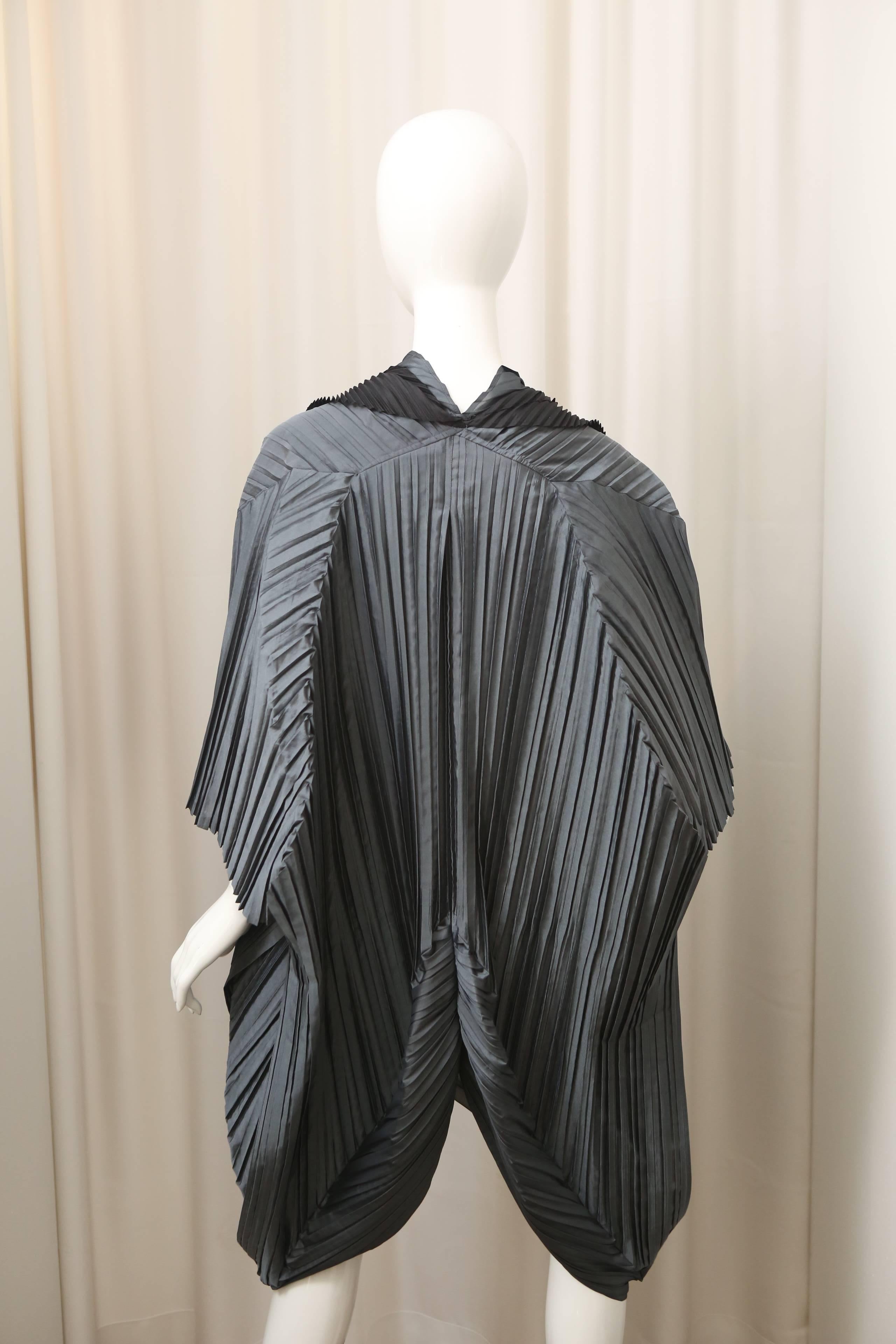 Issey Miyake grey pleated cape style jacket with black detail & button closure.