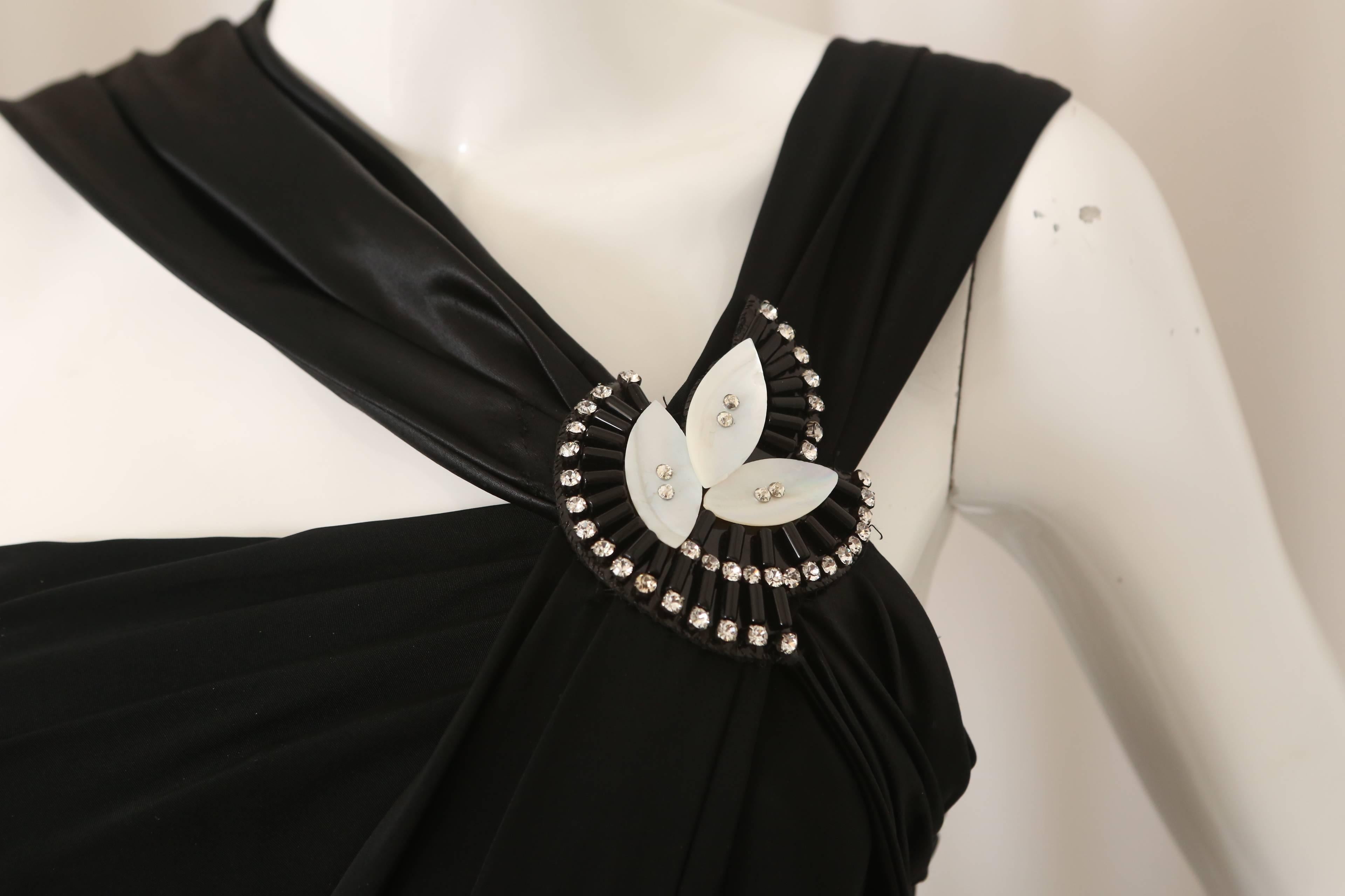 Gucci black cocktail dress w/ double straps on left shoulder & embellishment.  W/ patent leather tie belt at waist.  

Some damage on straps near embellishment.