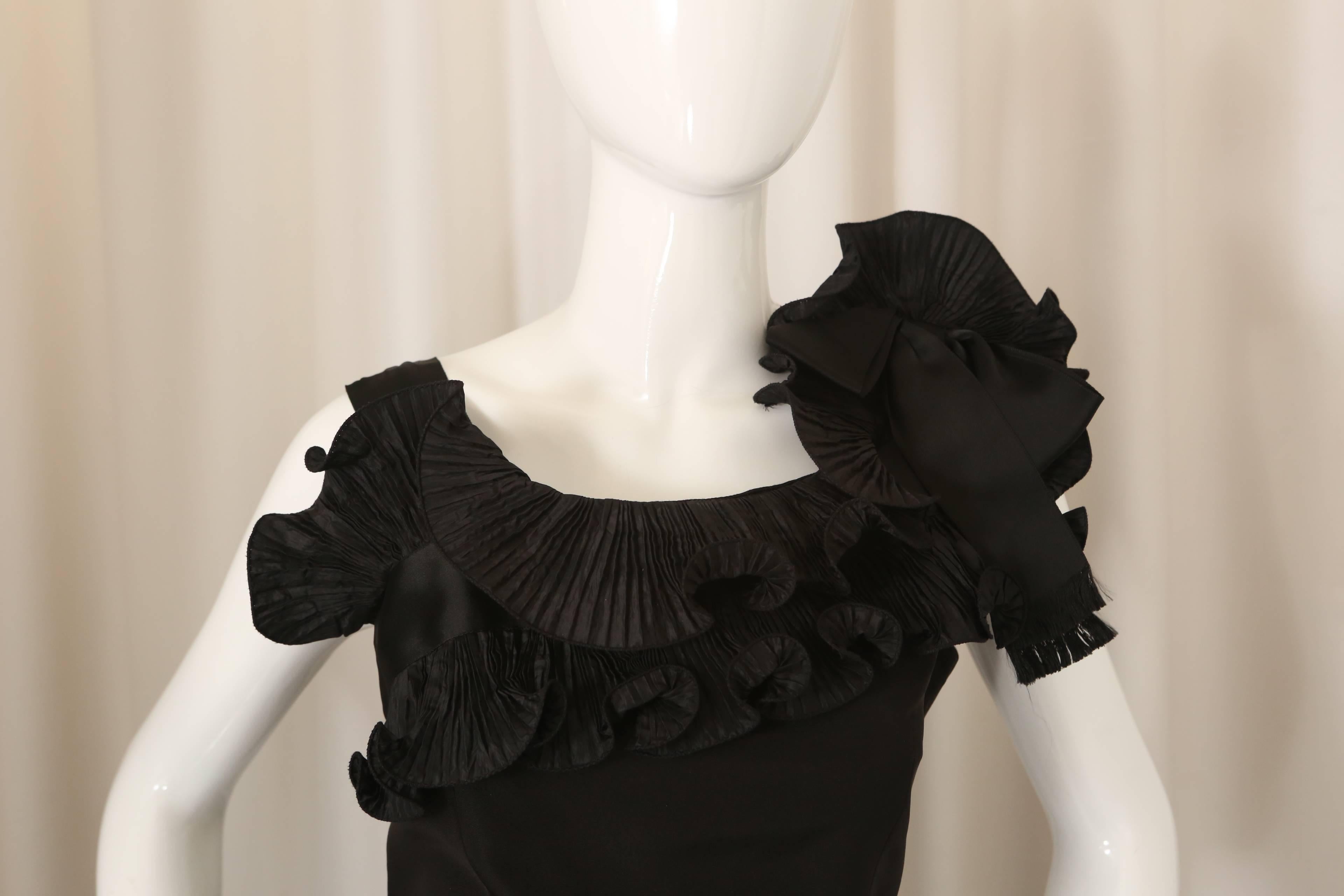 Oscar de la Renta black sleeveless cocktail dress with ruffles at neckline and bow on left shoulder. 
