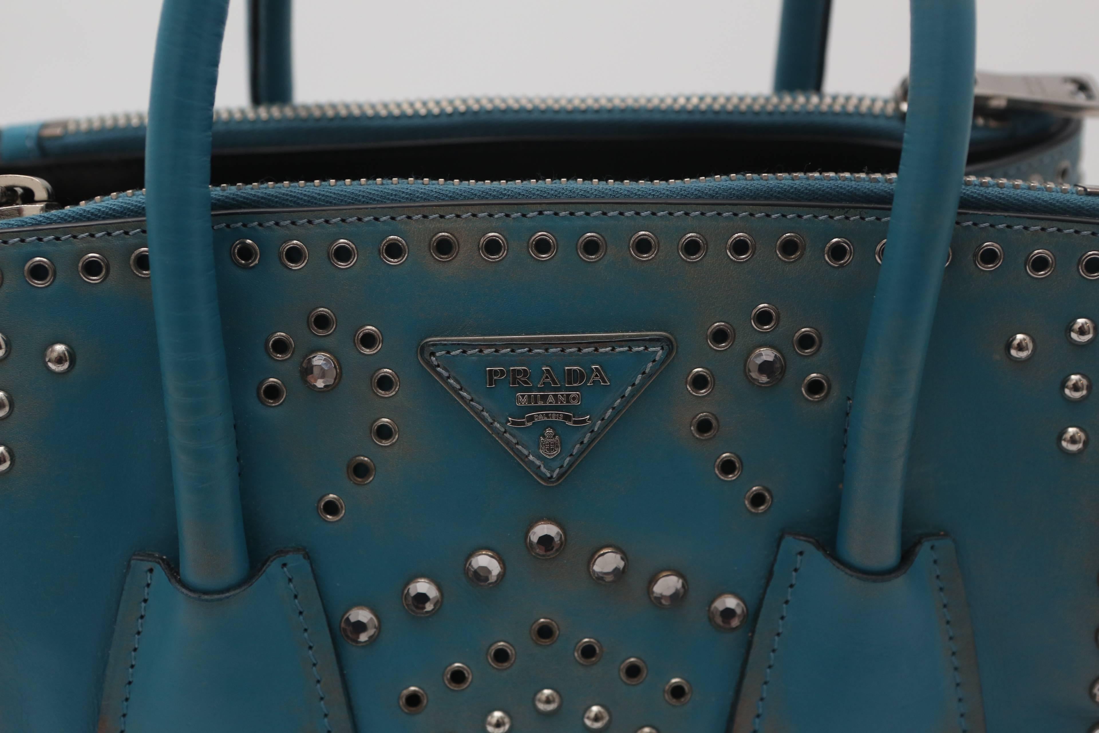 From the Fall/Winter 2014 Collection. Blue Prada vitello vintage embellished tote with silver-tone hardware, logo placard at front face, rivets and crystal embellishments, removable shoulder straps, dual rolled handles, dual zip pockets, interior