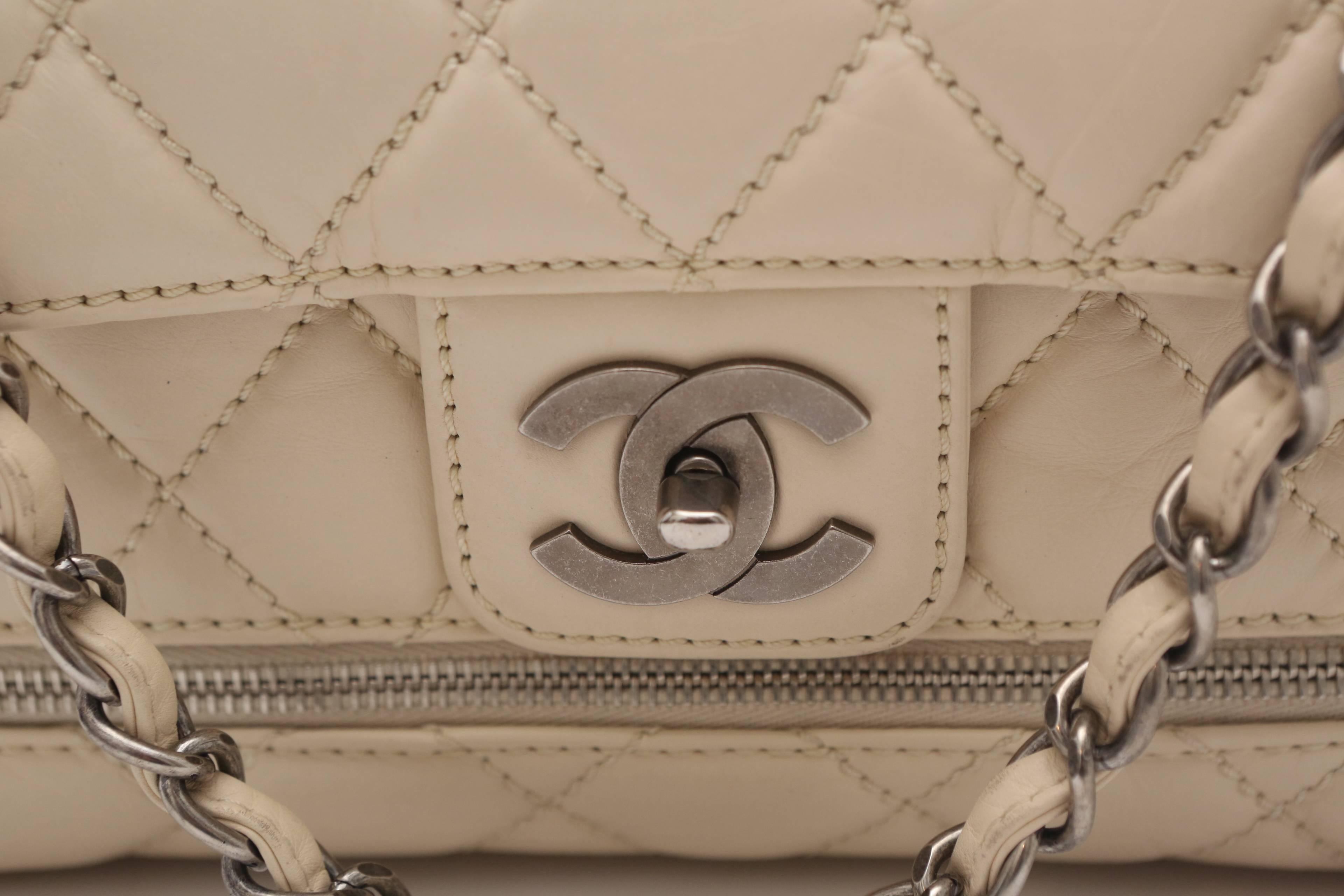 This Chanel Paris/New York (PNY) Expandable Flap Bag is made of Distressed Calfskin and Aged Silver hardware. CC turnlock closure on front and slip pocket on back. Right side of bag had logo embossed Silver plate. Zipper runs around base of bag and
