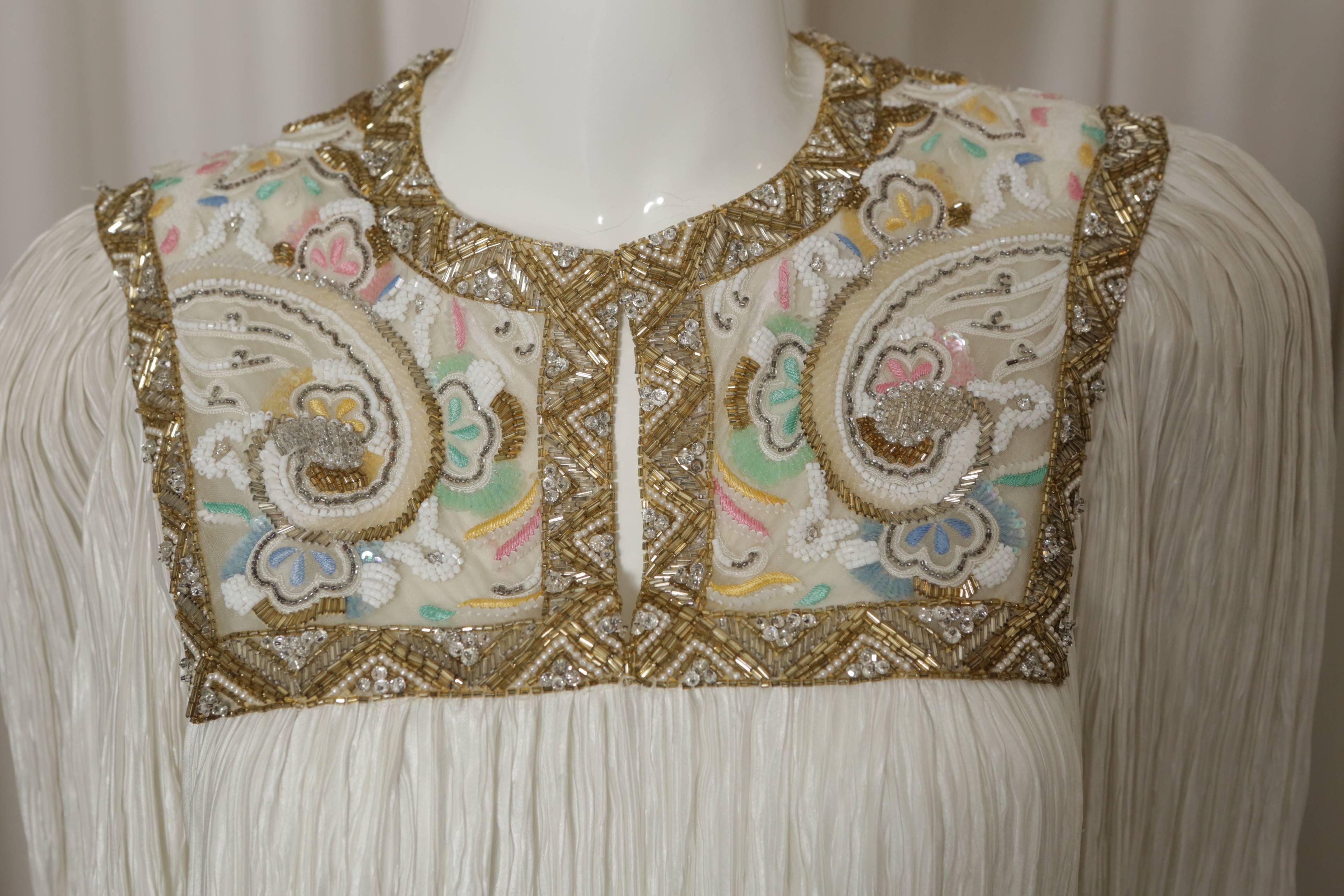 Mary McFadden short sleeve ivory/multi pleated dress w/ split 'V' & multi colored beading.

*S