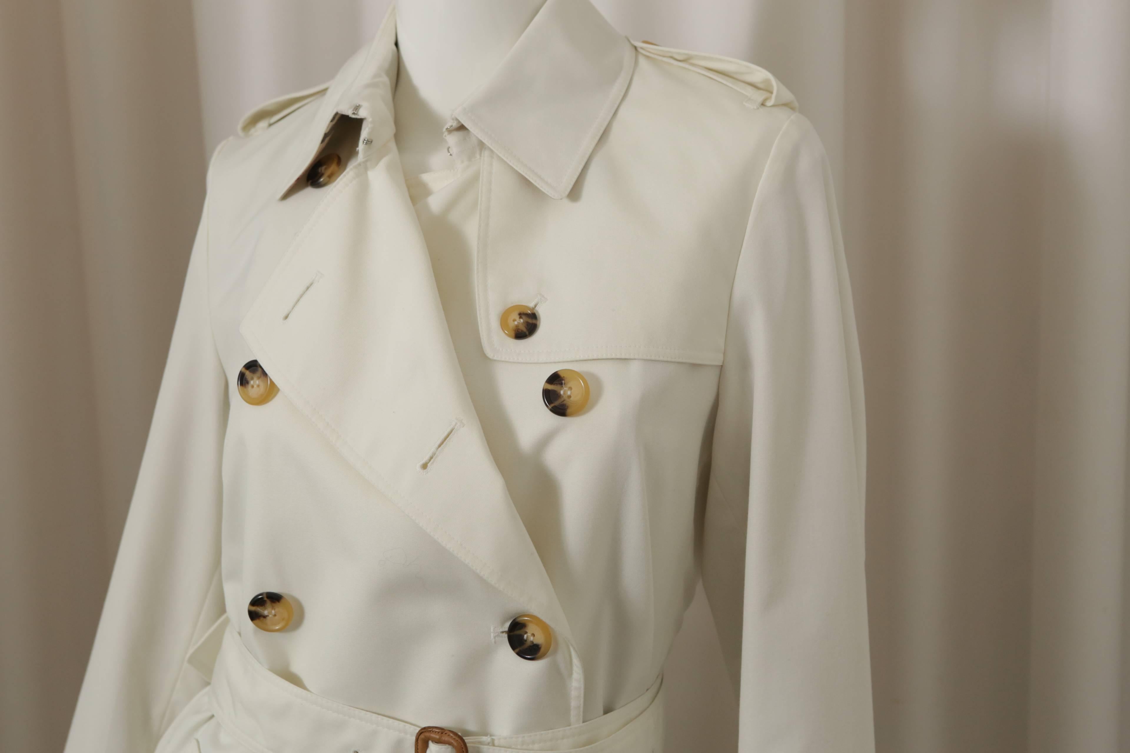 Burberry London classic ivory trench coat w/ tortoise doucble breasted buttons, belt, belts around wrists, & plaid lining. 