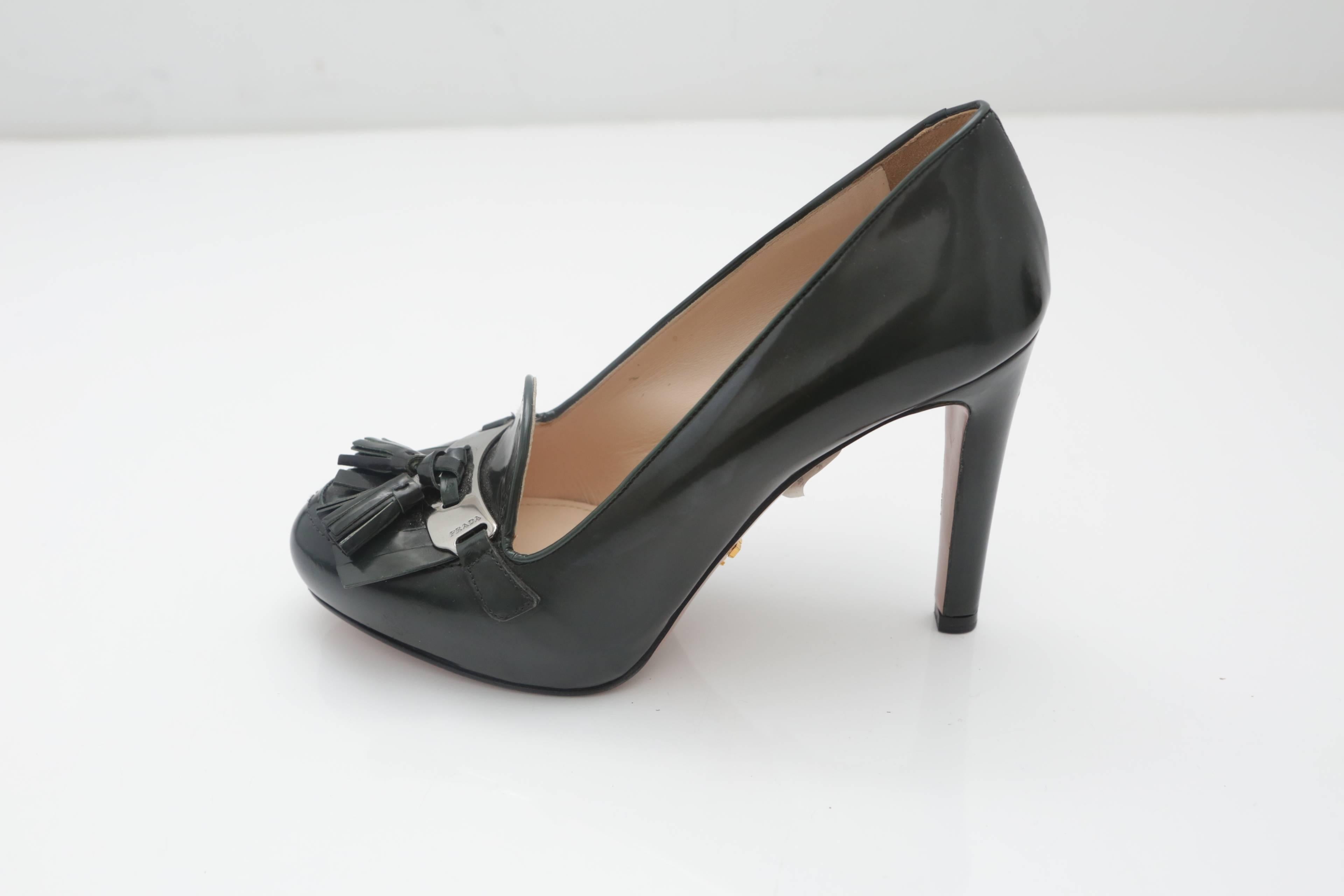 Prada patent leather green pumps with 4" heel, tassels, front logo and silver placket. Gold "Prada" placket on bottom.