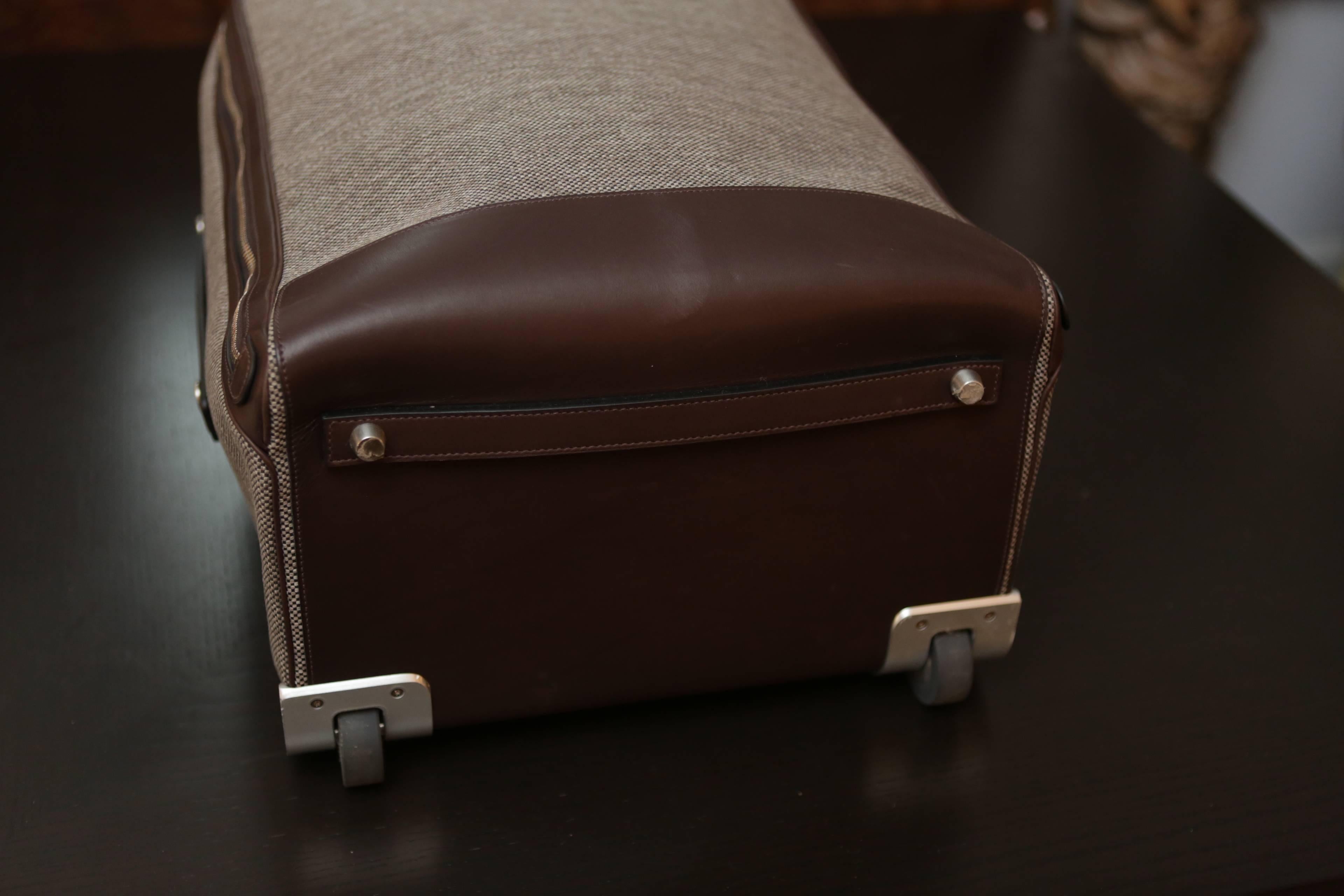 A classic and simple Hermes Caleche-Express carry-on cabine suitcase with wheels. Wool construction with leather trim, metal telescopic handle (with original removable protective stickers). Hermes branding on leather zippers and metal buttons. 