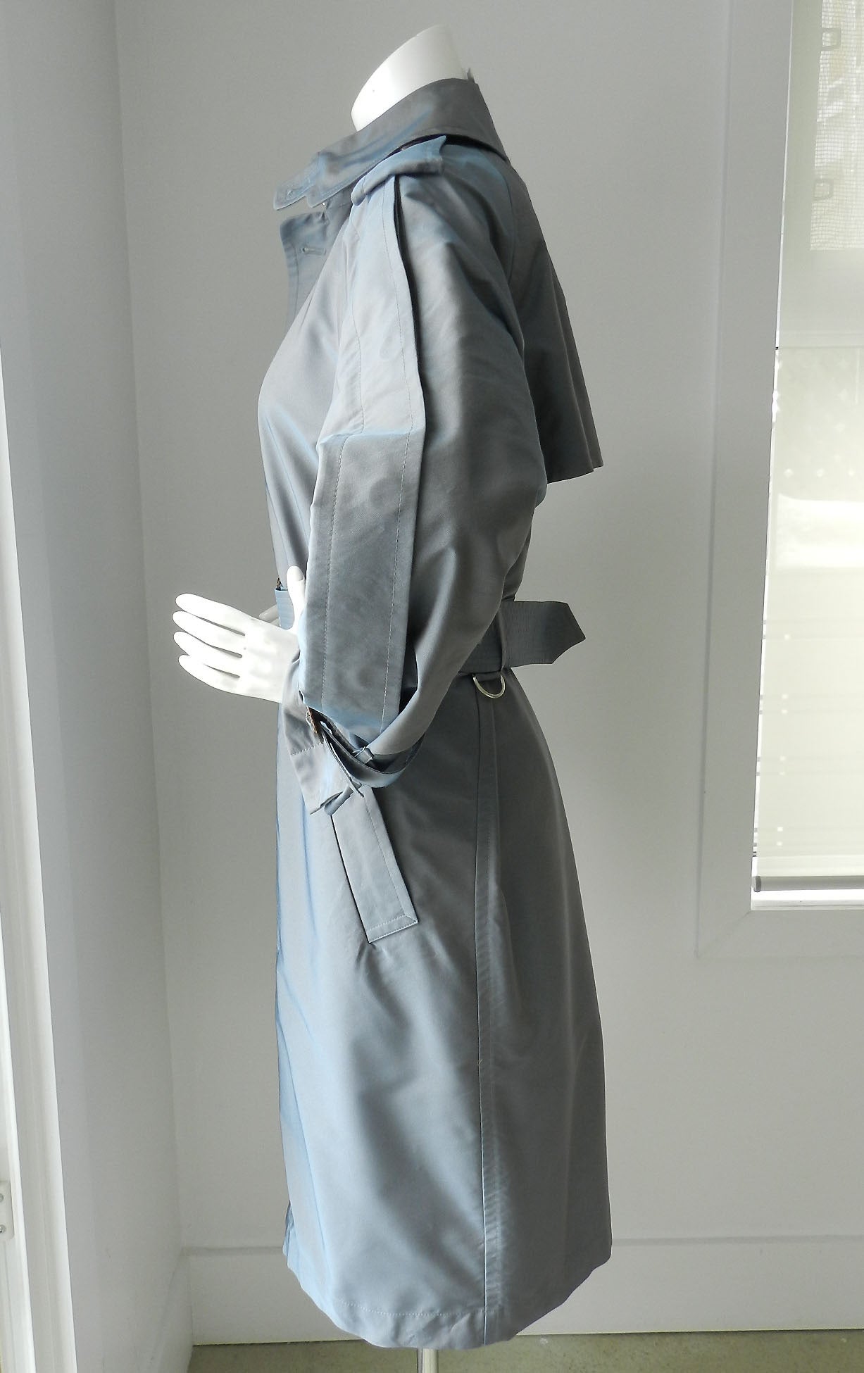 Jean Paul Gaultier pale greyish blue trench coat. Excellent previously owned condition. Fabric is 100% poly and has a slight iridescent sheen to it like sharkskin. Tagged size USA 4 but this can be worn by larger as it is cut oversized. Can fit an 8