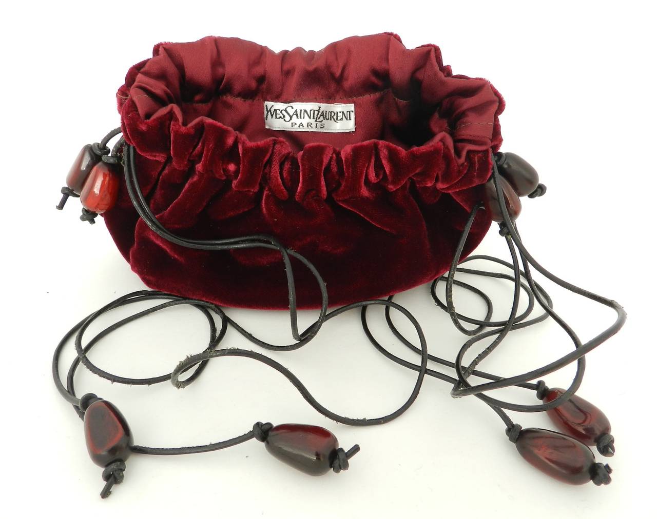 Small vintage YSL Yves Saint Laurent red velvet evening bag. Drawstring on leather cords with tagua nut beads. Circa 1990's. Body measures about 5 x 4.5 x 2.5