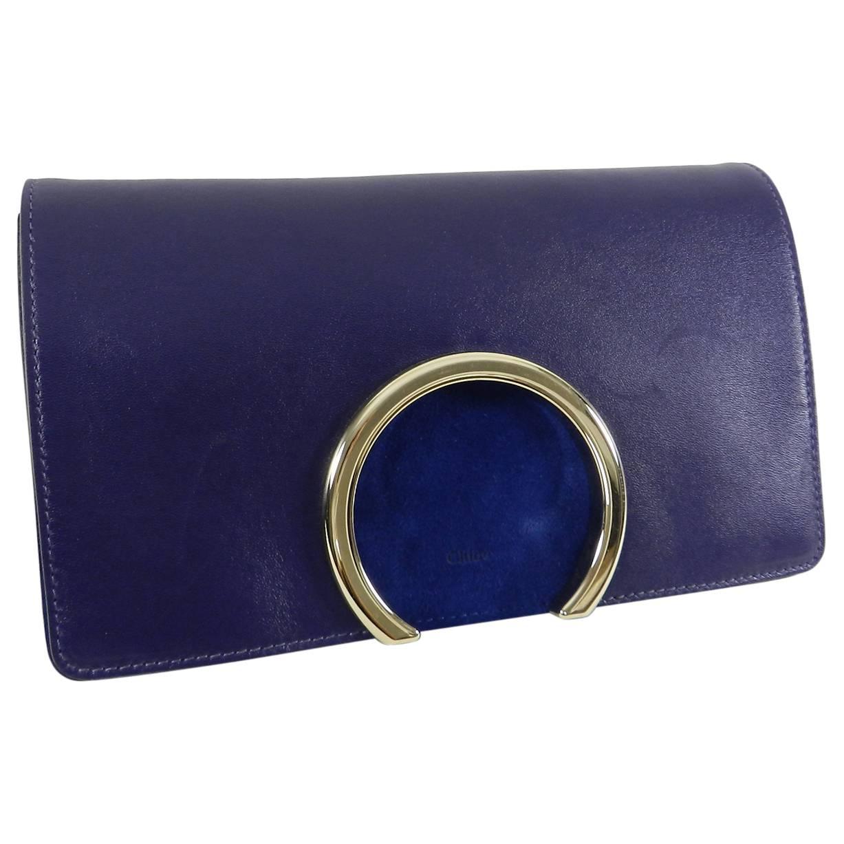 Navy smooth calfskin leather and suede clutch with magnetic closure gold tone hardware. Lined with nude leather, zipper centre compartment, excellent pre-owned condition. Measures 10”x 6”x 1.75”.