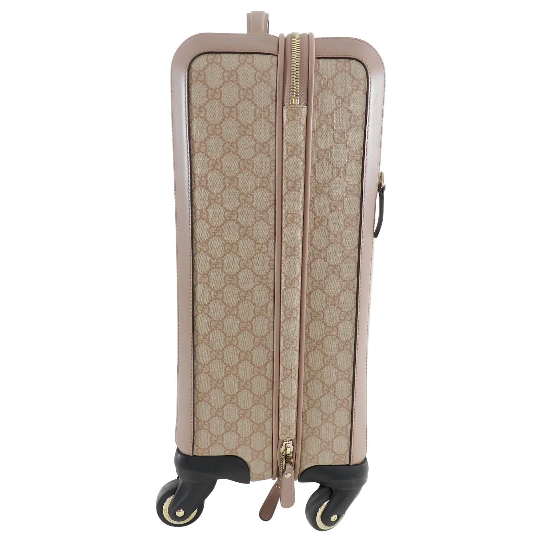 Gucci GG Supreme Monogram 4 Wheel Rolling Carry-on Luggage.  Monogram canvas and leather trim in beige and Winter Rose.  Goldtone metal trim, extendable pull-up handle, canvas lined interior. Measures about 21.25