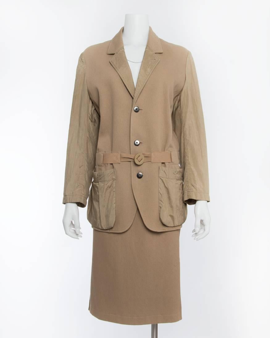 Issey Miyake Vintage 1980’s Cotton/ Nylon Tan Skirt Suit. Notched collar, front wooden toggle closure, with nylon sleeves and pockets. Skirt has side pockets, elastic waist, and pleated nylon inset at back.  Tagged size M but recommended for about