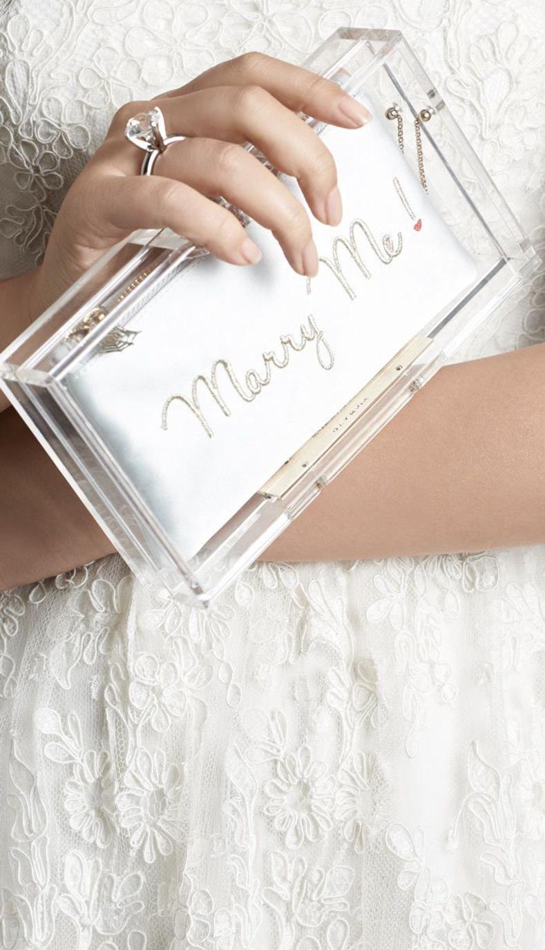 Charlotte Olympia Marry Me Acrylic Clutch Bag.  Faux diamond solitaire wedding ring clasp, magnetic closure, clear acrylic body.  Includes three separate inserts:  Satin with gold embroidery, ivory lace, and leopard calfskin.  Measures 7-⅜” x 4.25 x