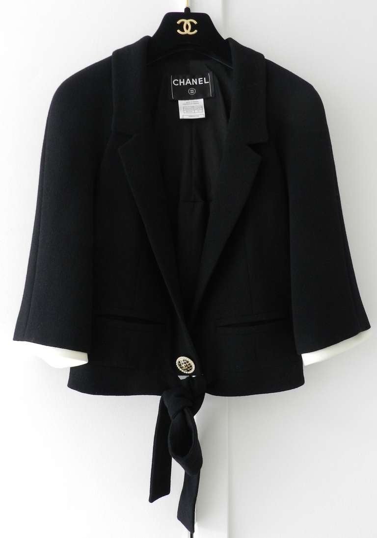 Chanel 2007 Spring collection black wool jacket. 3/4 sleeves with white trim, gold button with black enamel and pearls, tie sashes at front. Excellent condition. Tagged Chanel size 36 (USA 4). To fit 34