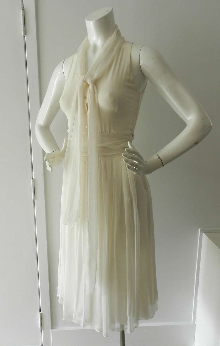 Christian Dior ivory silk chiffon sleeveless dress.  Buttons at front chest, long silk ties at neck, hidden side zipper. Original size tag has been removed but is FR 34, USA 0, XS. To fit 32/33” at bust, 24/25” waist and 33/34” hip.

Shipping