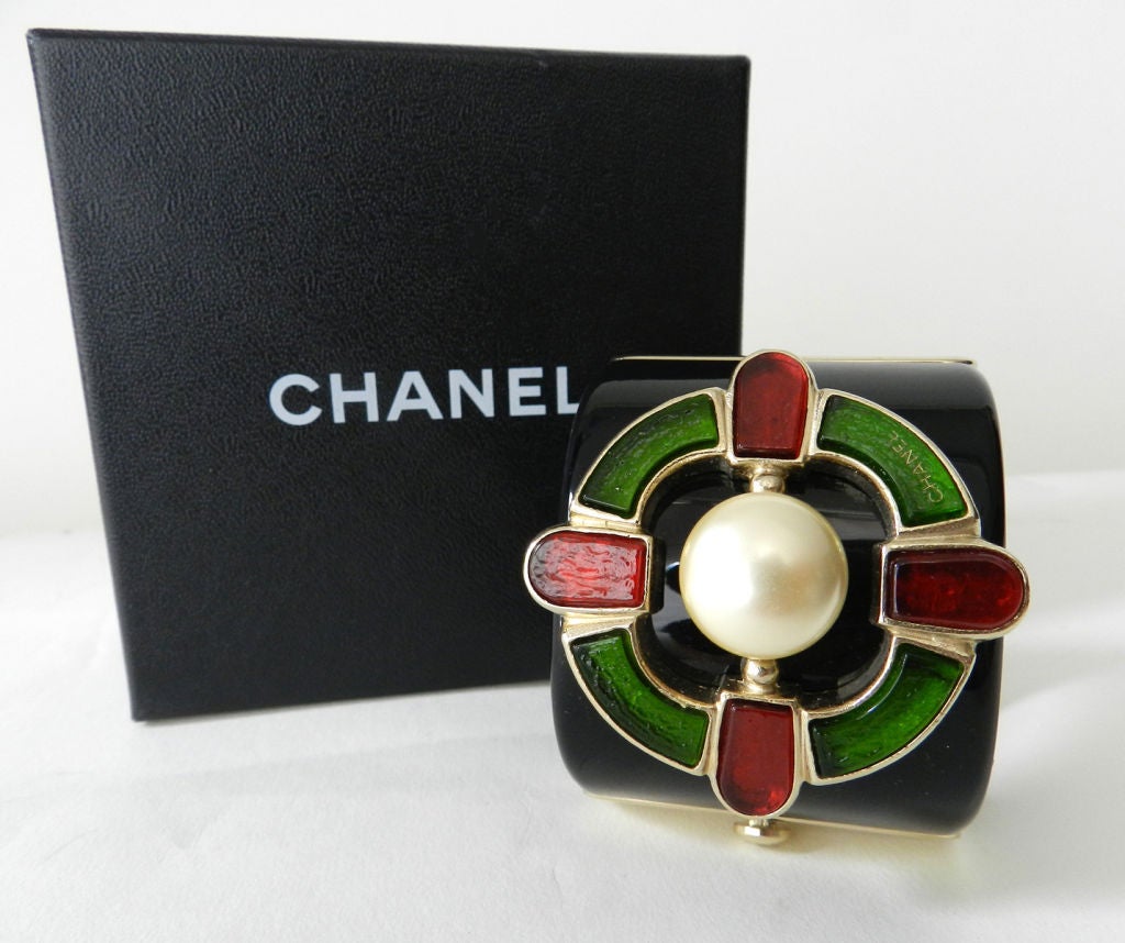 Chanel Gripoix glass Monte Carlo collection cuff bracelet from pre-fall 2007. Black lucite with red and green glass and centre faux pearl. Perfect unworn condition with original store sticker inside. Measures 2 inches wide and 6.75 inches interior