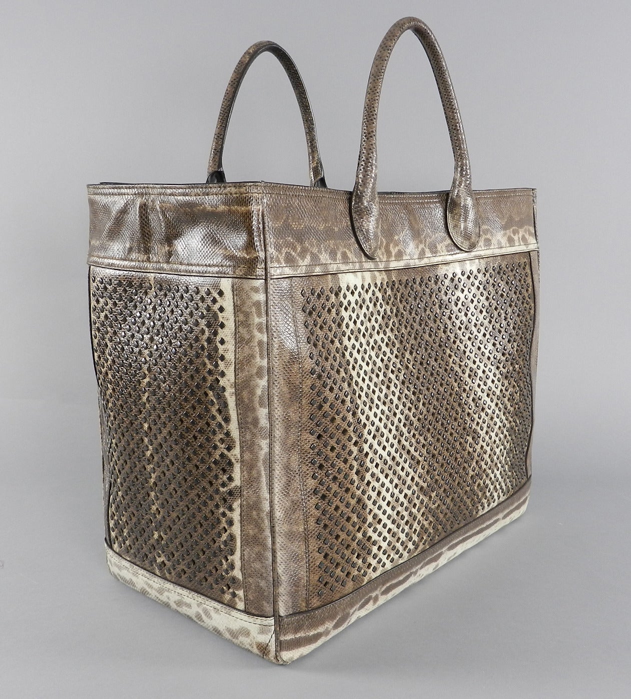 Alaia jumbo size lizard skin tote bag. Perforated design with metal stud detailing. Interior has a small zippered make-up bag and mirror. Pre-owned but in perfect clean condition. Body of bag measures 16