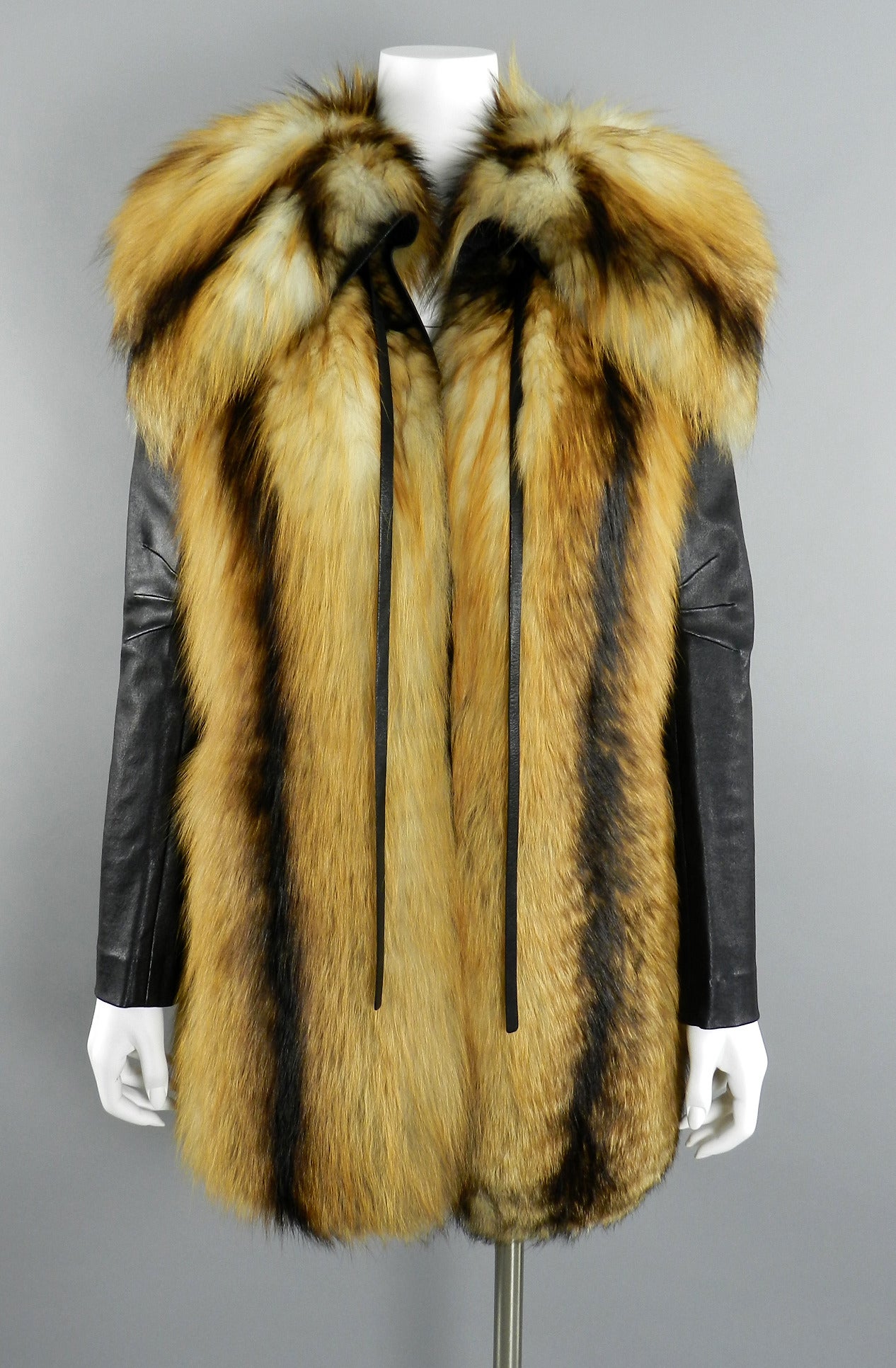 J. Mendel red fox fur coat with removable leather sleeves. Converts into vest.  Light fall-weight so not a heavy winter coat. Stretch leather sleeves snap on and of. Sides of vest have slits up to the waist and have a black leather buckle accent.