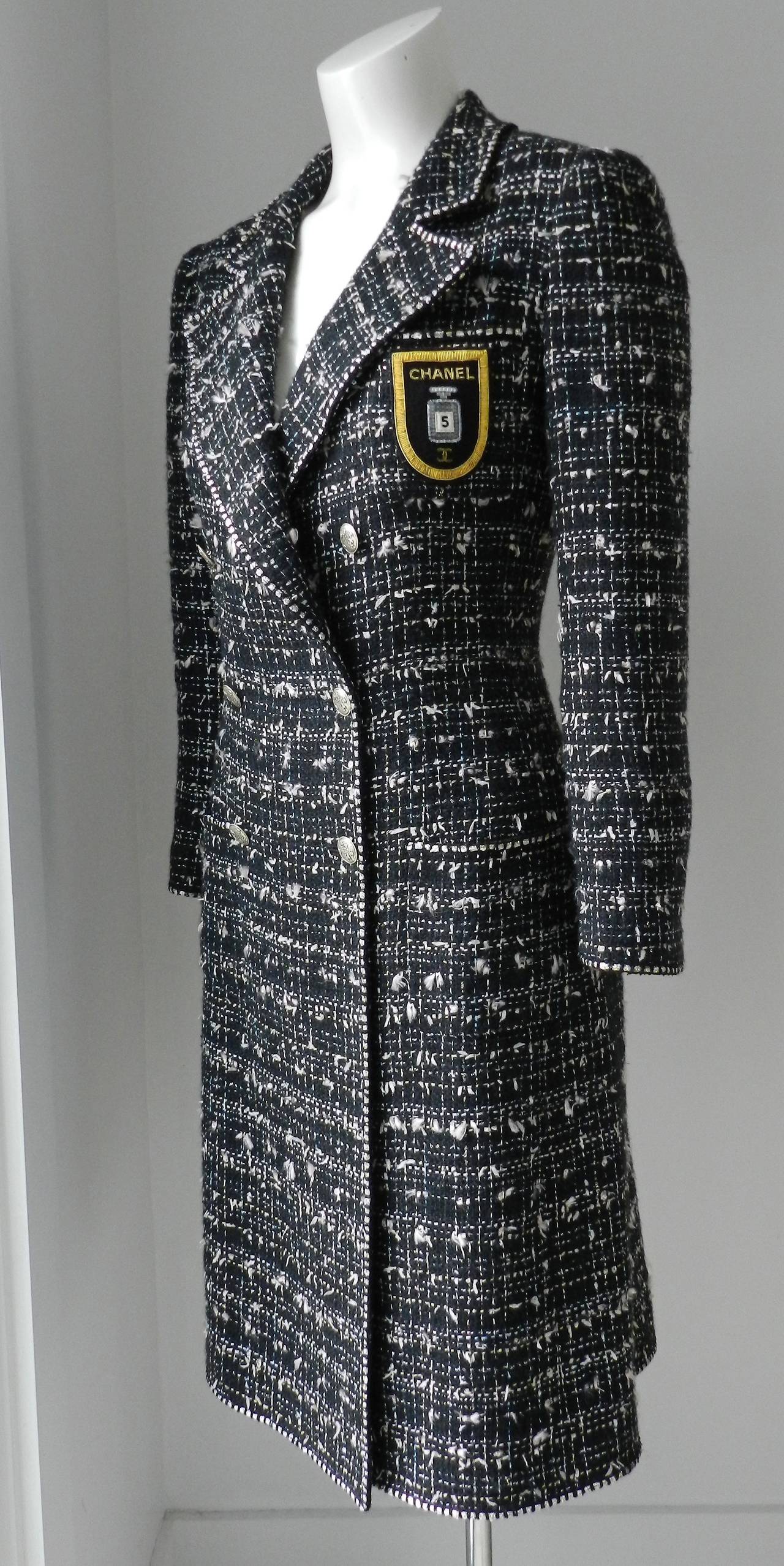 Chanel 2005 resort collection long tweed jacket. Body is black with light pink, silver, and ivory tweed accents.  Gold metallic embroidered CC chanel no. 5 perfume badge, silvertone CC buttons, lined in silk. Tagged size FR 36 but fits like a