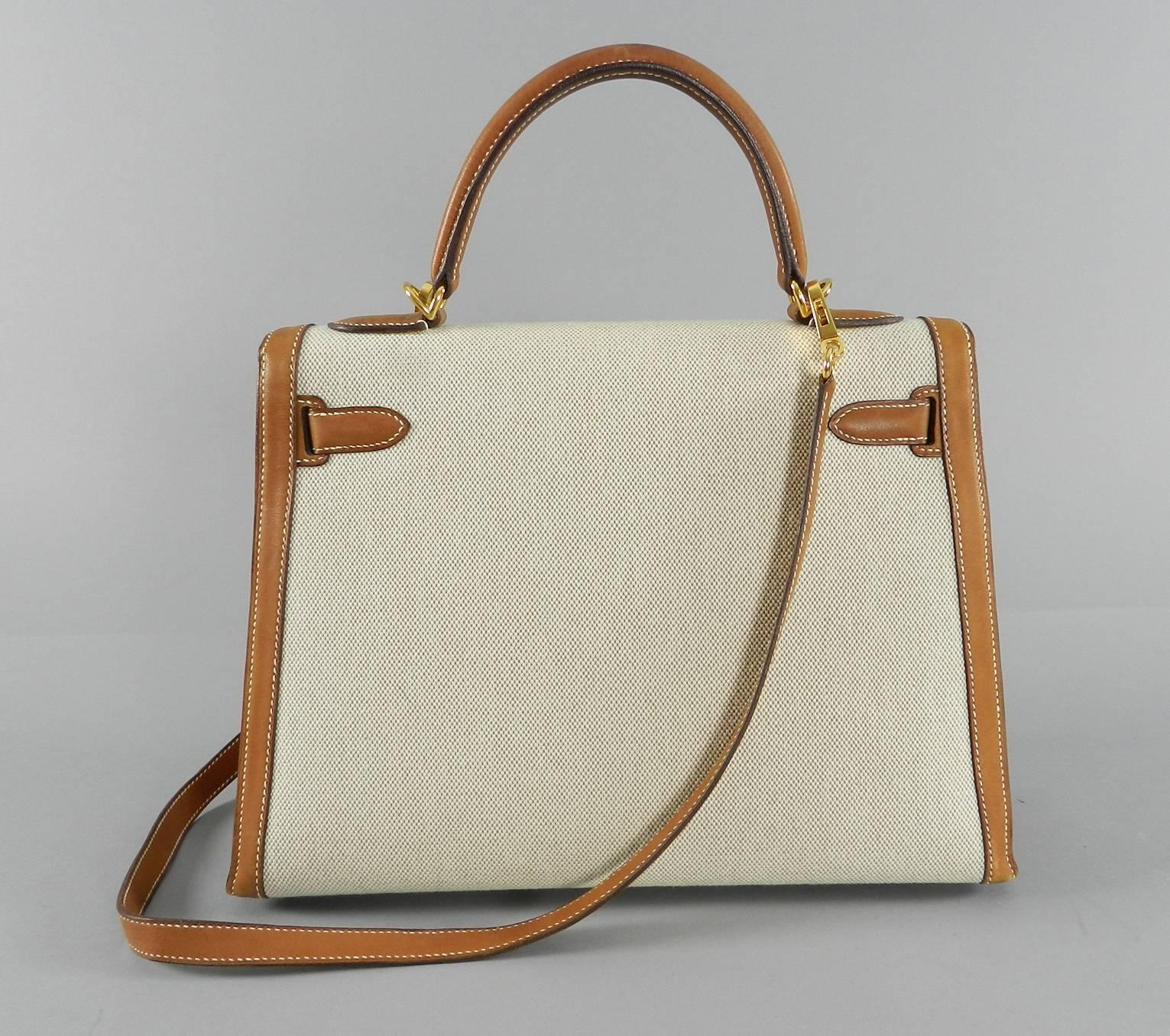 Hermes Kelly 32cm bag in bi-color barenia natural leather and toile canvas. Used only a few times. Excellent pre-owned condition with some darkening to top handle as pictured, but overall excellent condition. Comes with clochette, clochette duster,